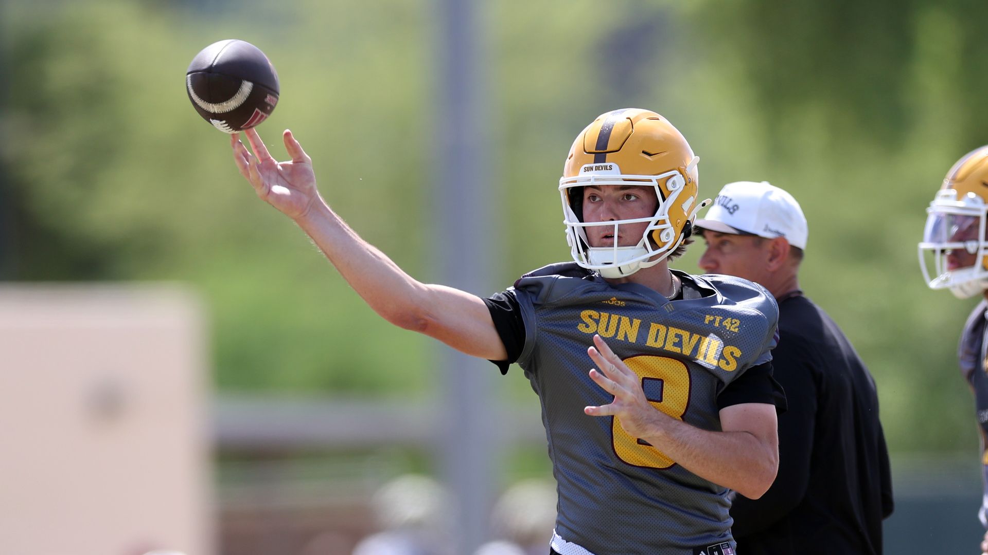 ASU quarterback Cutter Boley, in a grey jersey with yellow numbers and black shorts and a yellow helmet, throws a pass during a practice.