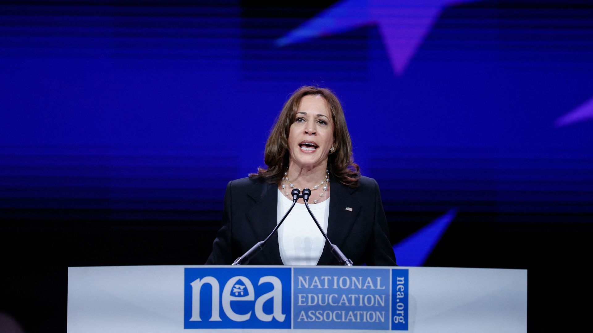 Photo of Kamala Harris speaking from a podium that has a sign says "National Education Association"