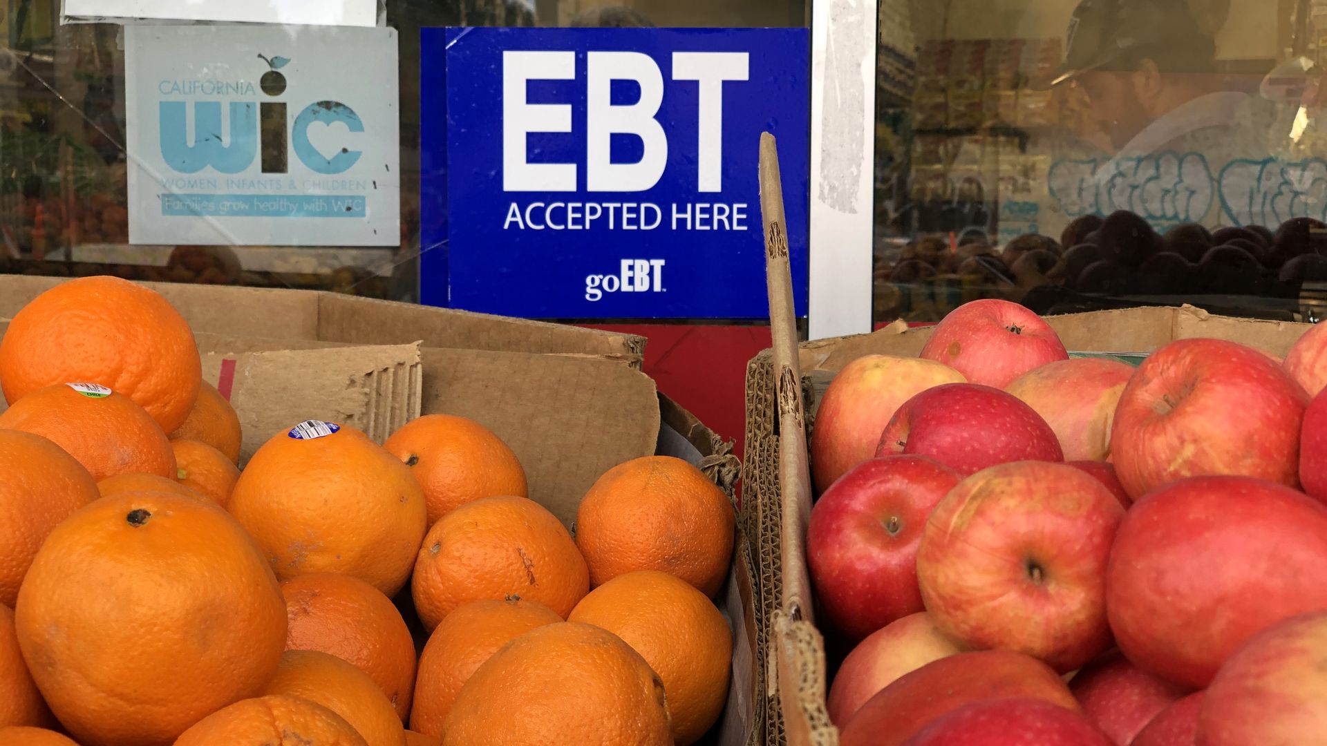 A sign in a grocery store window reads “EBT accepted here,” referring to food assistance benefits.