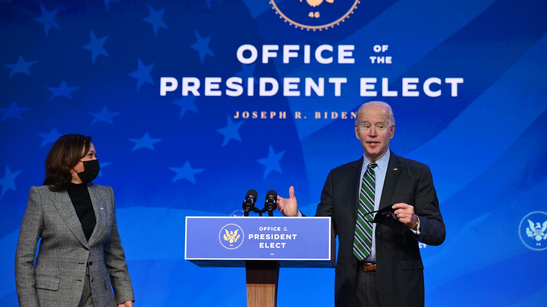 Biden stands with Kamala Harris under a screen that reads "Office of the President Elect"