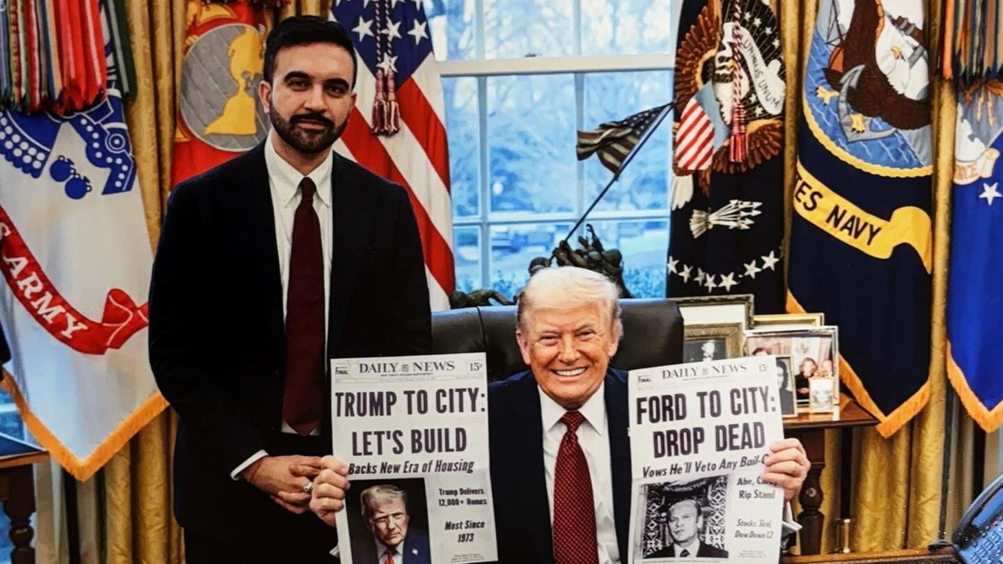 Man in suit standing beside smiling Donald Trump seated in the Oval Office, both holding up newspapers with bold headlines about city housing and political promises.