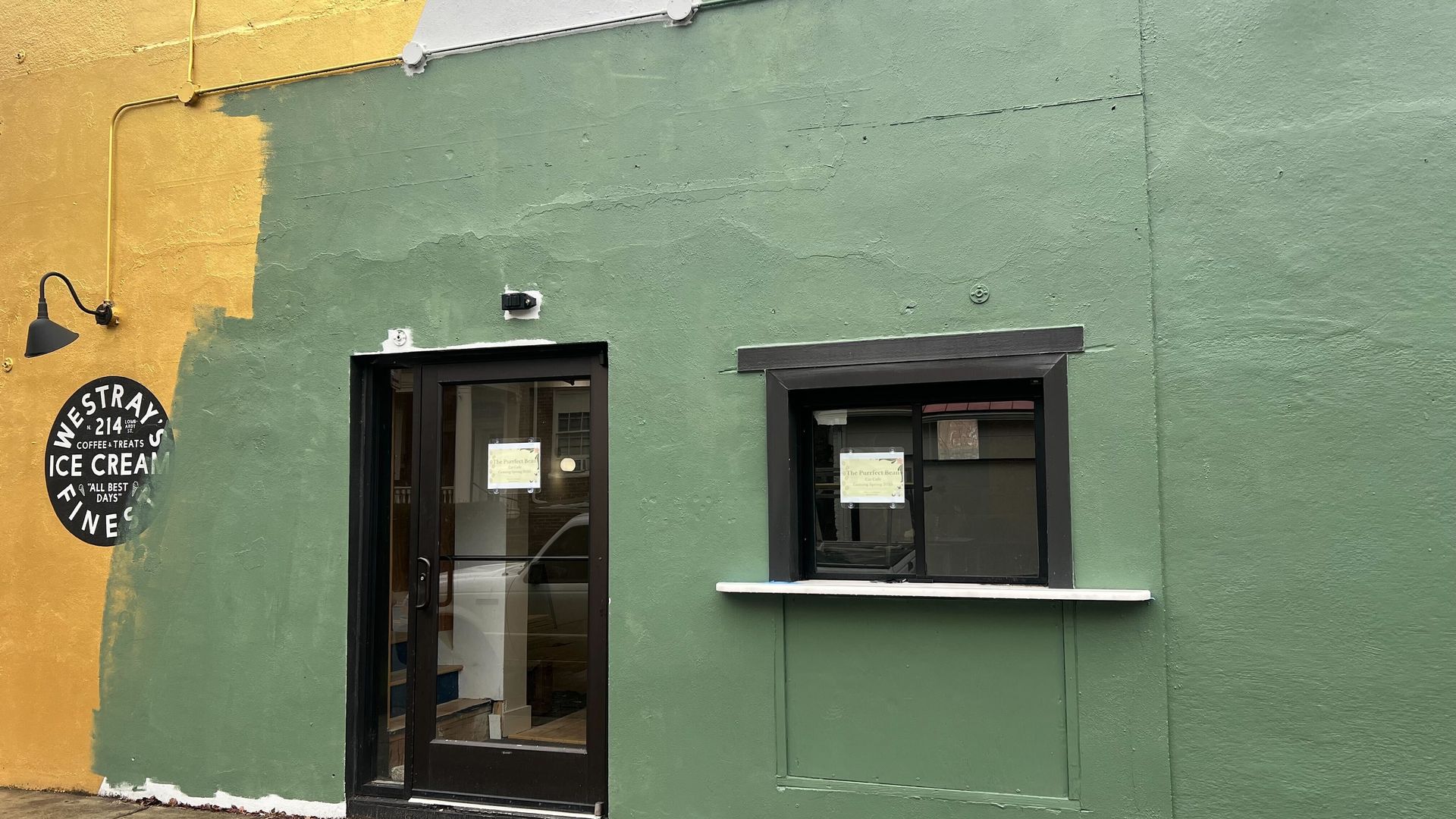 A green and yellow building with a takeout window 