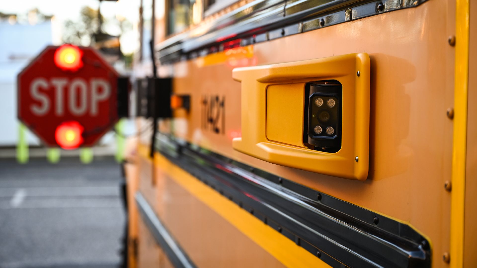 A school bus has its "STOP" sign arm opened with a camera attachment 