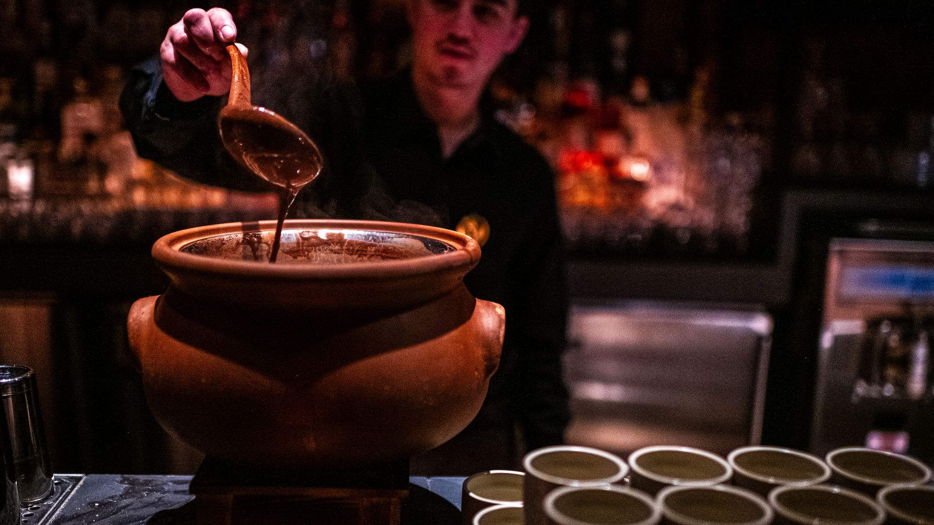 A man ladles liquid cacao into a vessel 