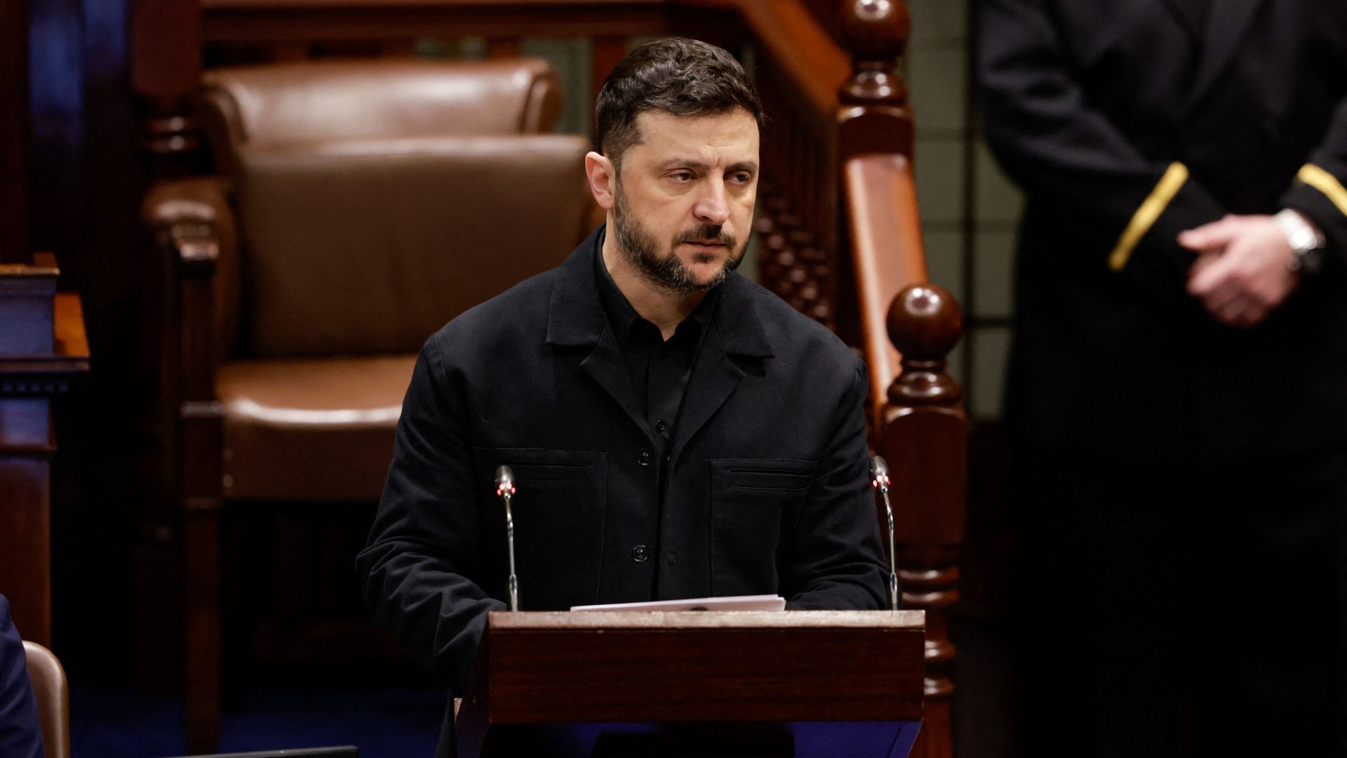 Volodymyr Zelensky standing at a lectern in the Dáil Chamber, delivering remarks to Irish lawmakers.