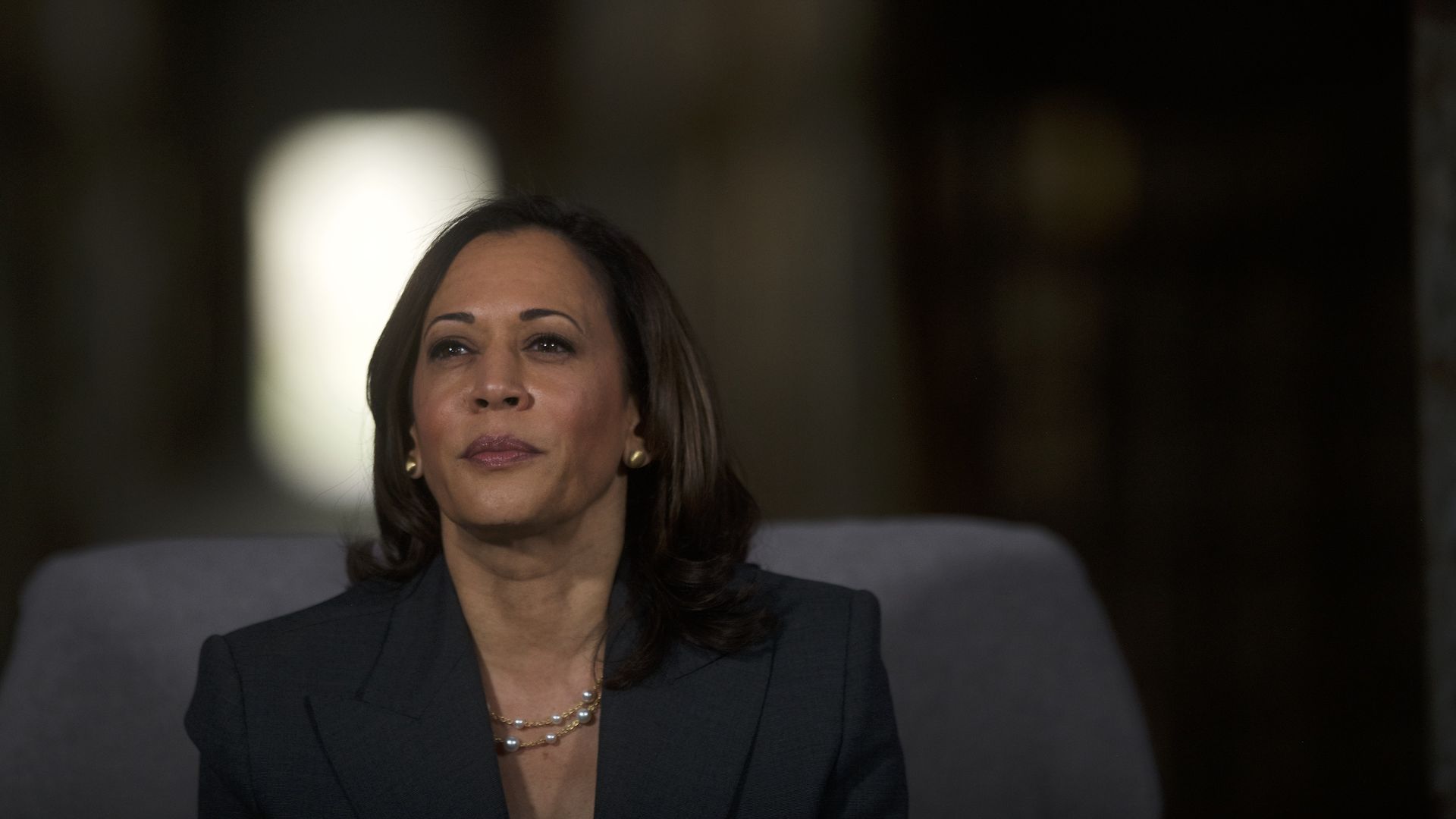In this image, Kamala Harris sits and looks to the left