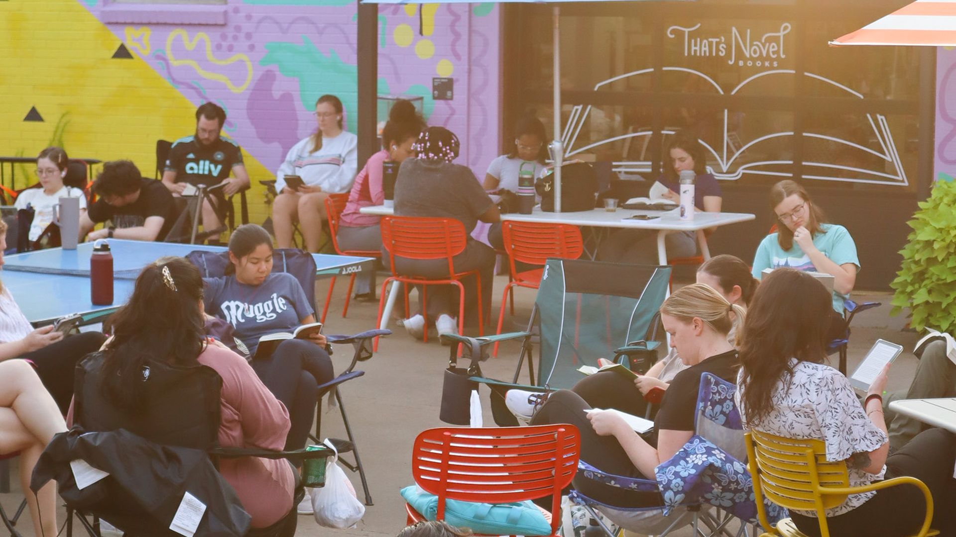 People sit outside of That's Novel Books at Camp North End for Silent Book Club. 