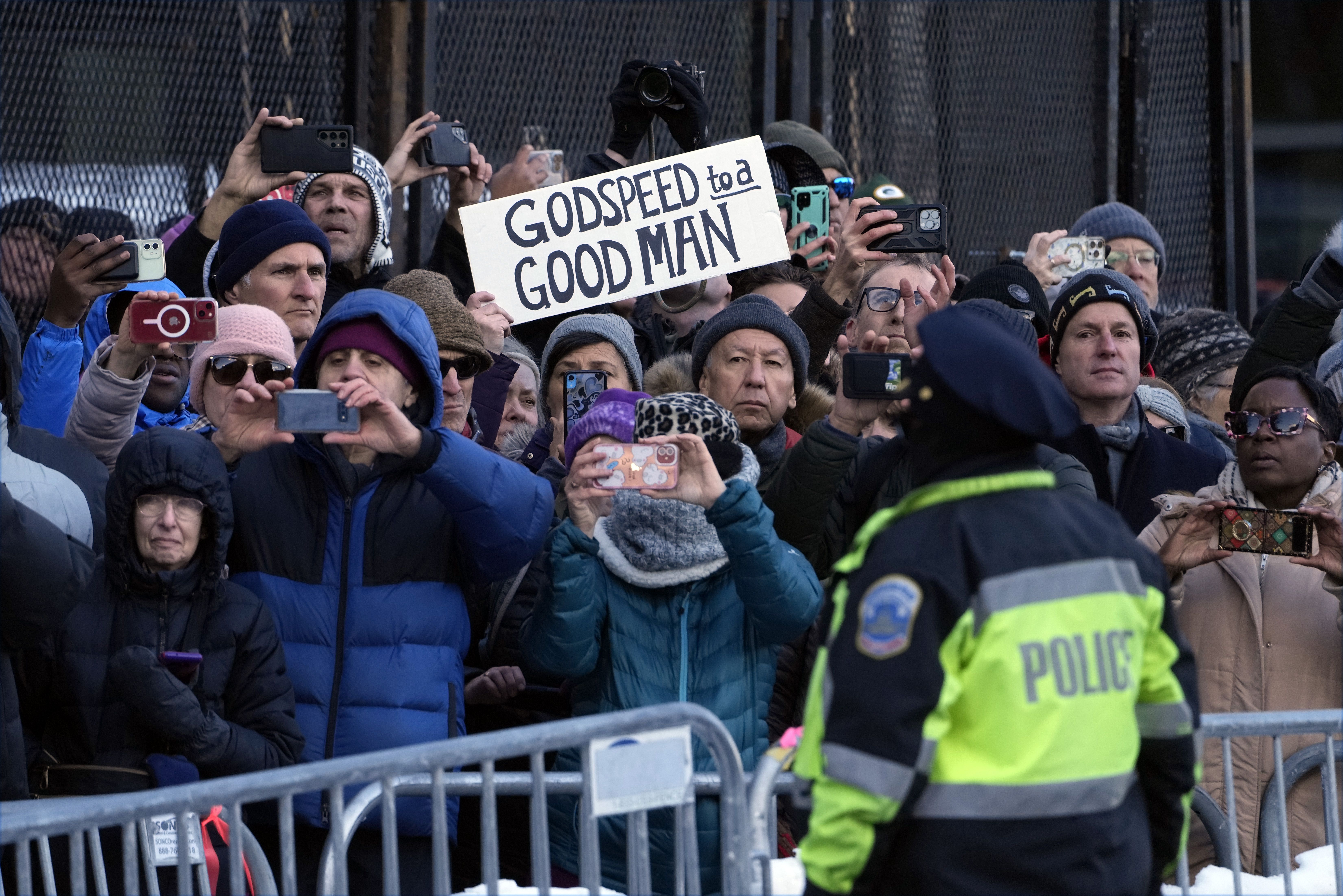 A photo of a crowd of people lining up to pay their respects during former President Jimmy Carter's funeral procession.