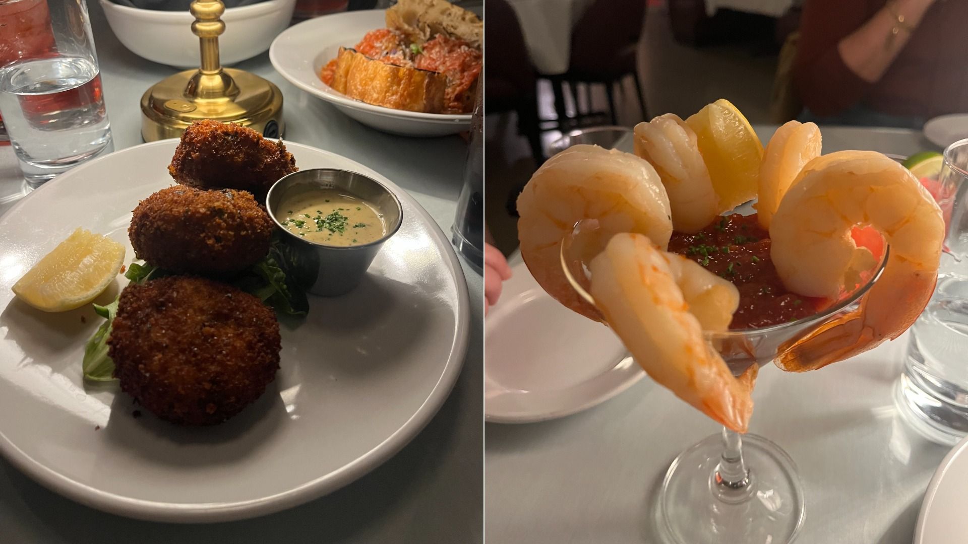 Two plates of seafood appetizers. Left: three dark brown crab cakes with dipping sauce and lemon wedge on a white plate. Right: a shrimp cocktail in a glass with shrimp arranged around cocktail sauce and lemon.