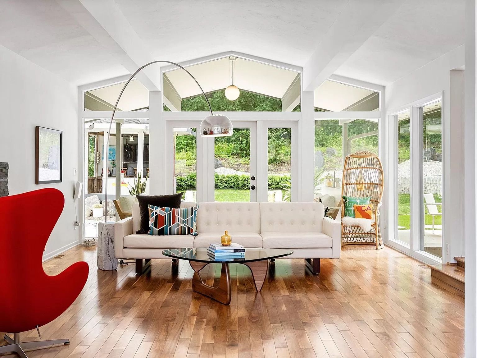 A living room with floor to ceiling windows, a white couch and a gold lamp.