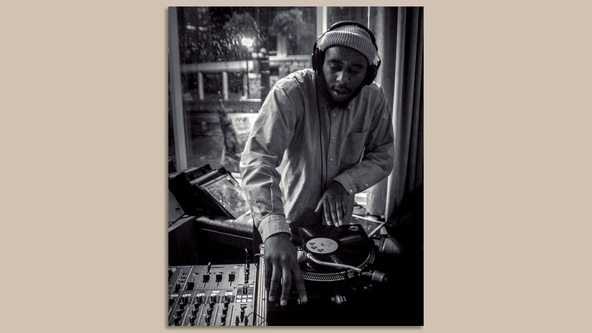 A photo of a person wearing headphones and deejaying on a record table.