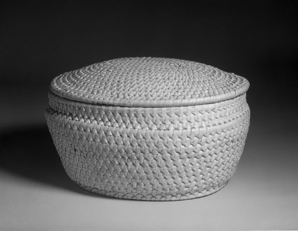 A photograph of a woven basket with a lid.