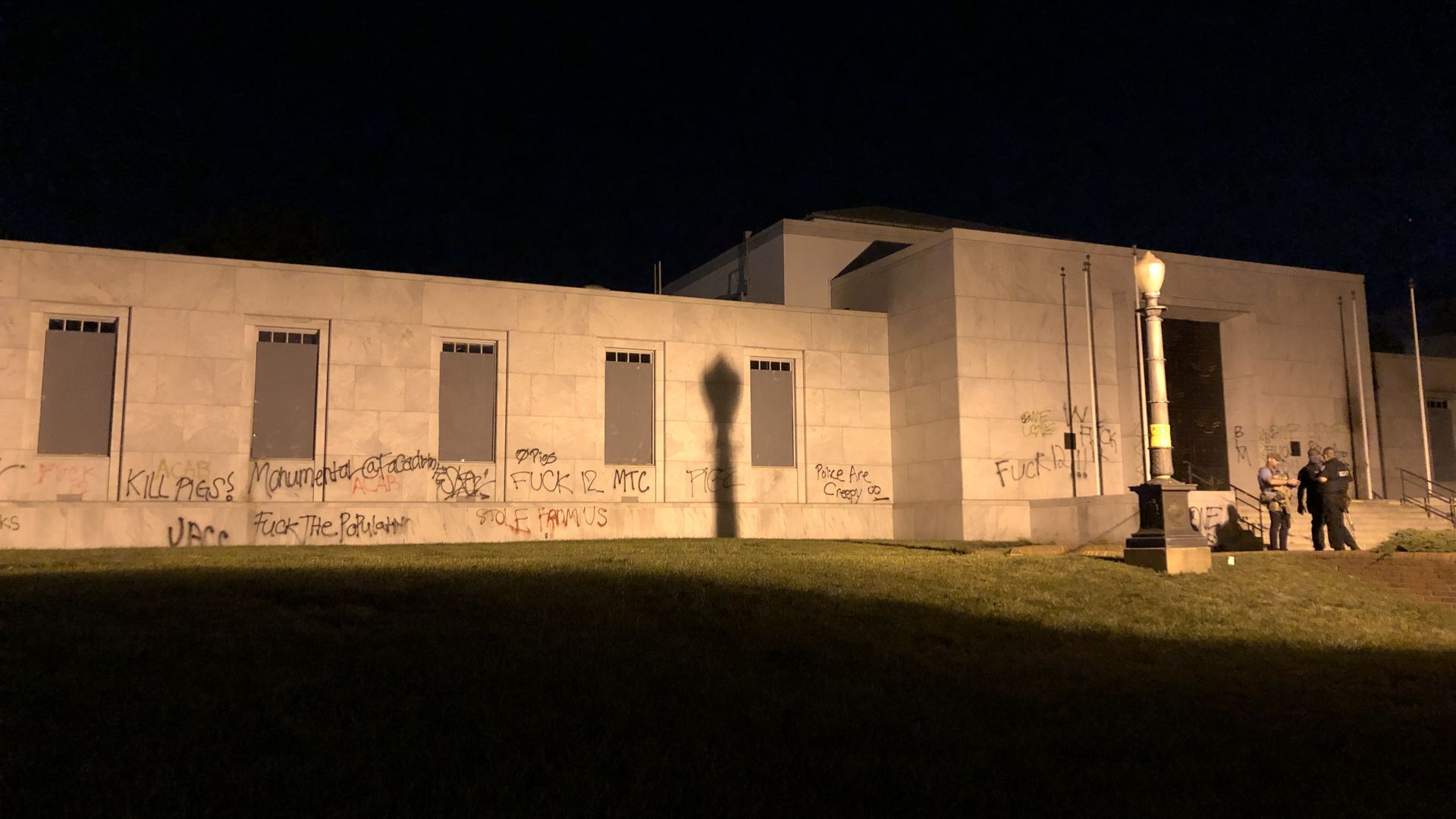 a building with guards in front of it and graffiti everywhere
