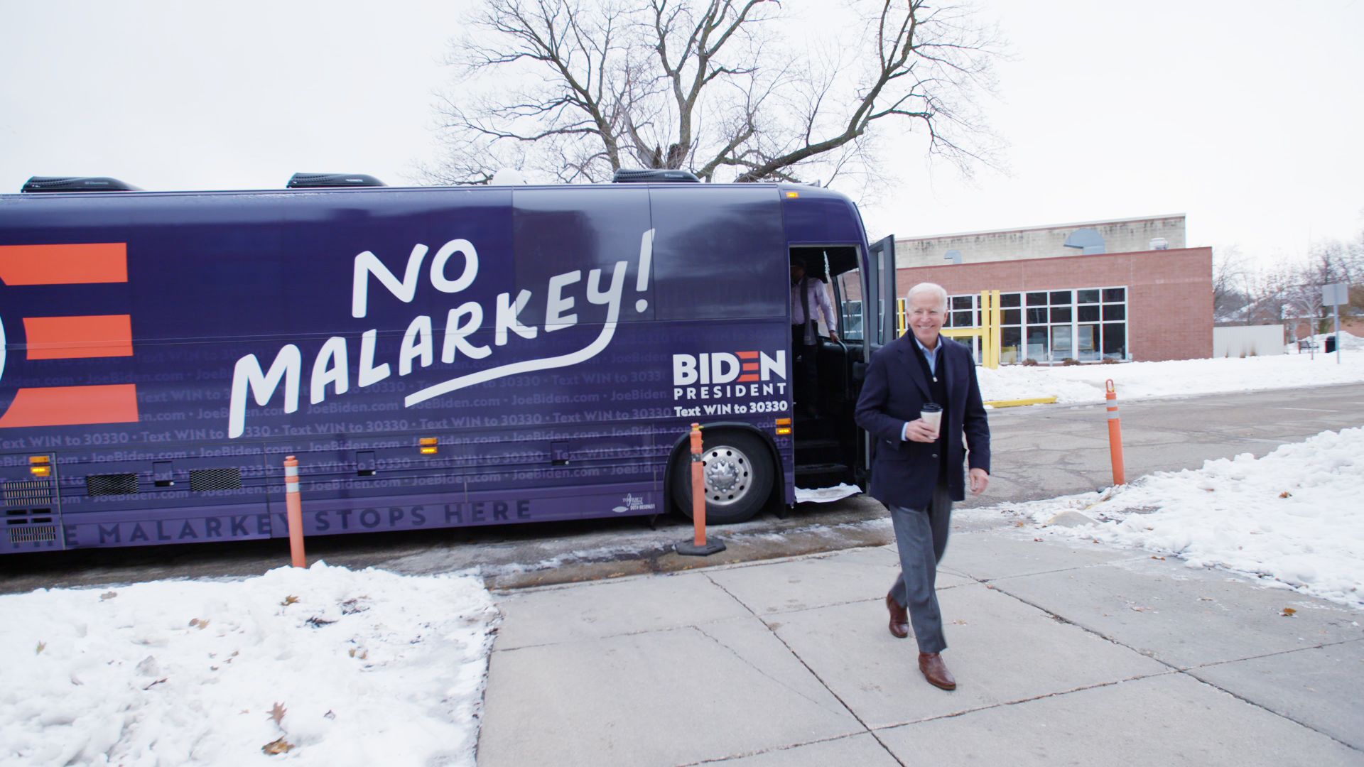 Joe Biden walks in front of a bus with No Malarkey painted on the side
