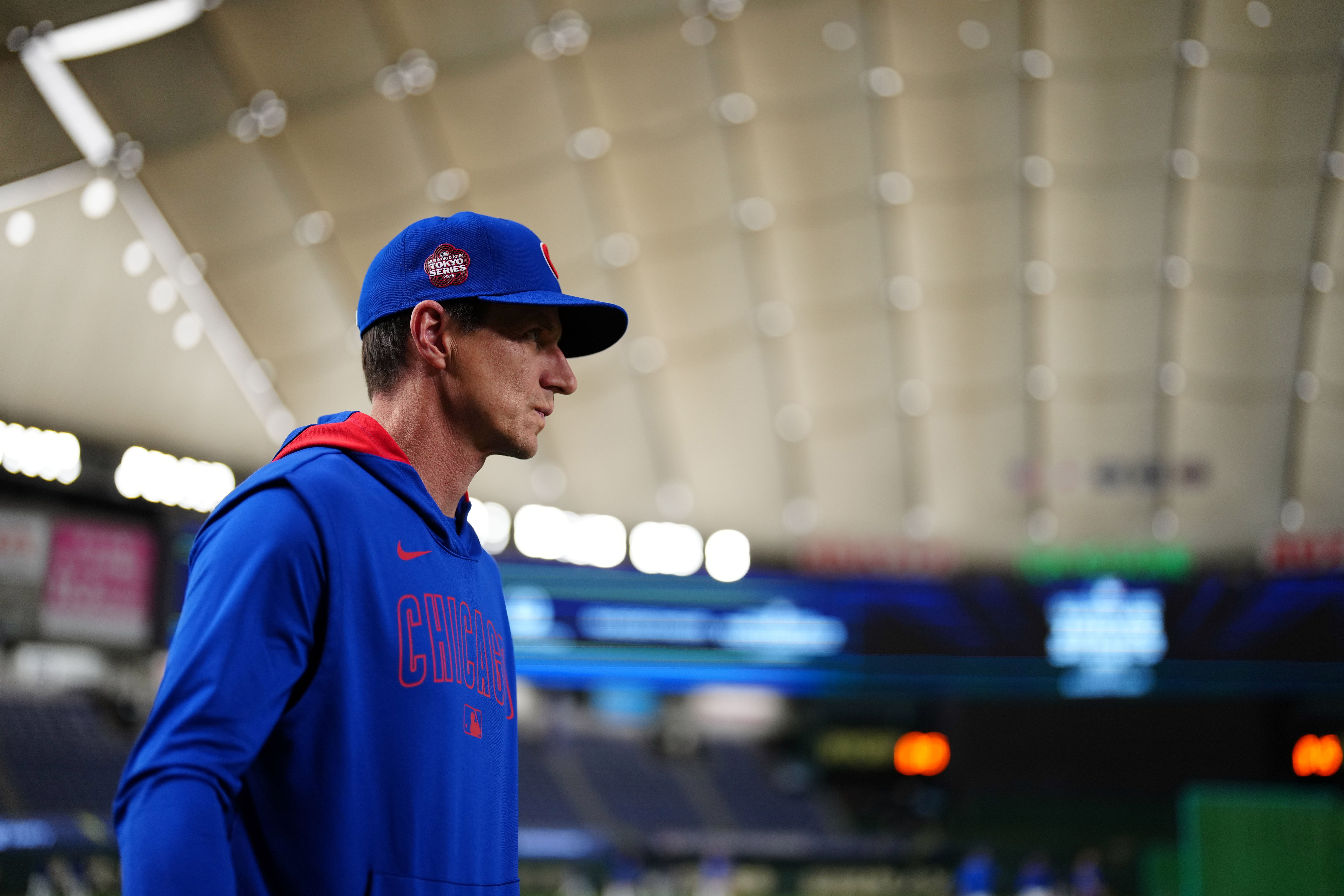 Photo of a man in a baseball uniform walking on a field inside a domed stadium. 