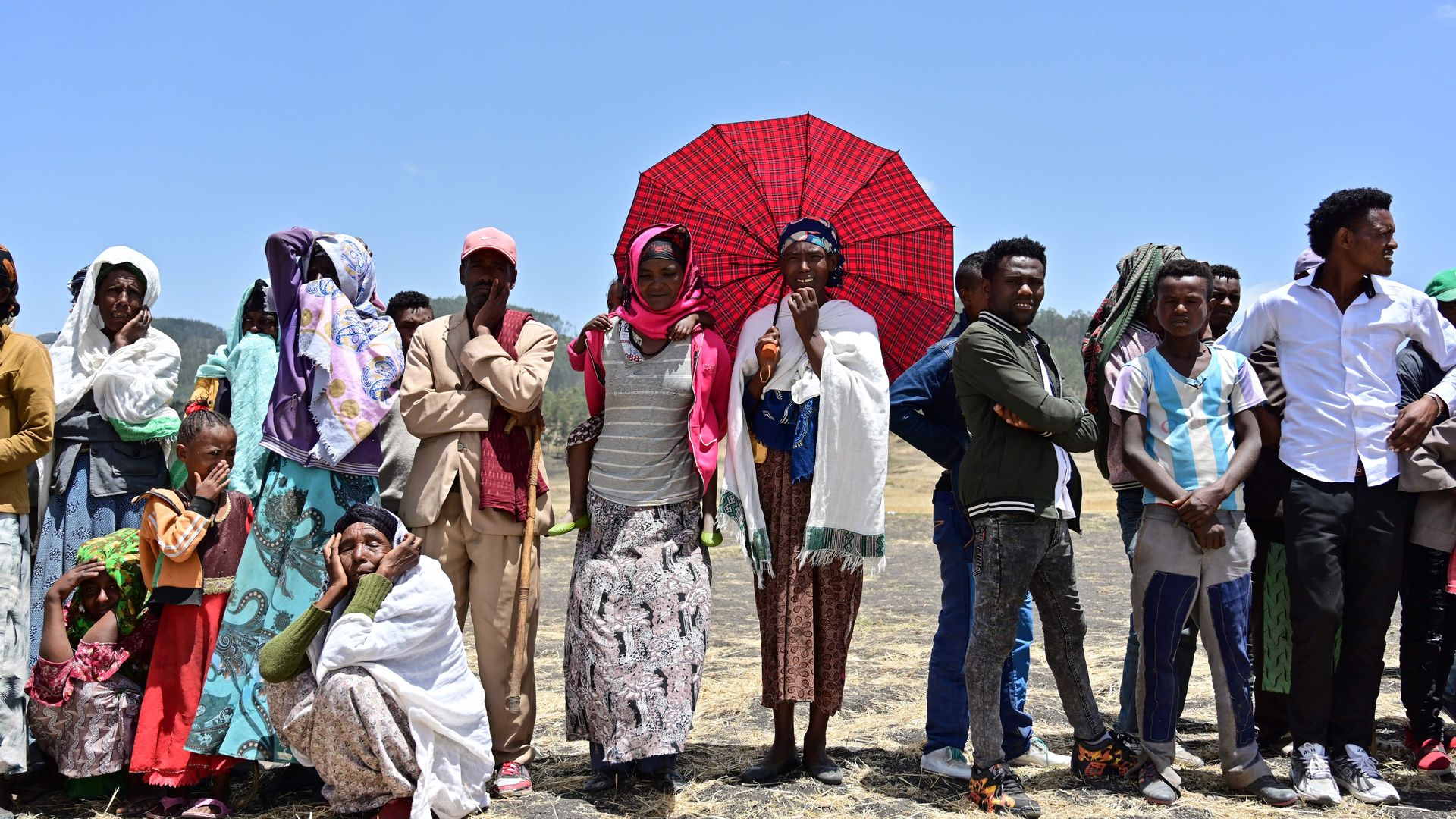 People in colorful clothing weep at the site where  an Ethiopian Airlines Boeing 737 MAX  crashed in 2019. 