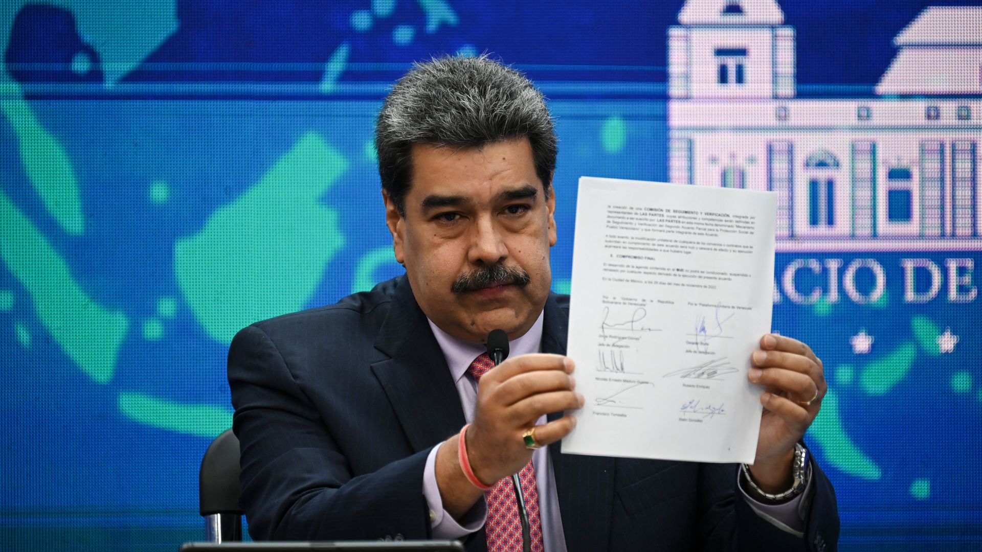 Venezuelan leader Nicolás Maduro holds up a piece of signed paper