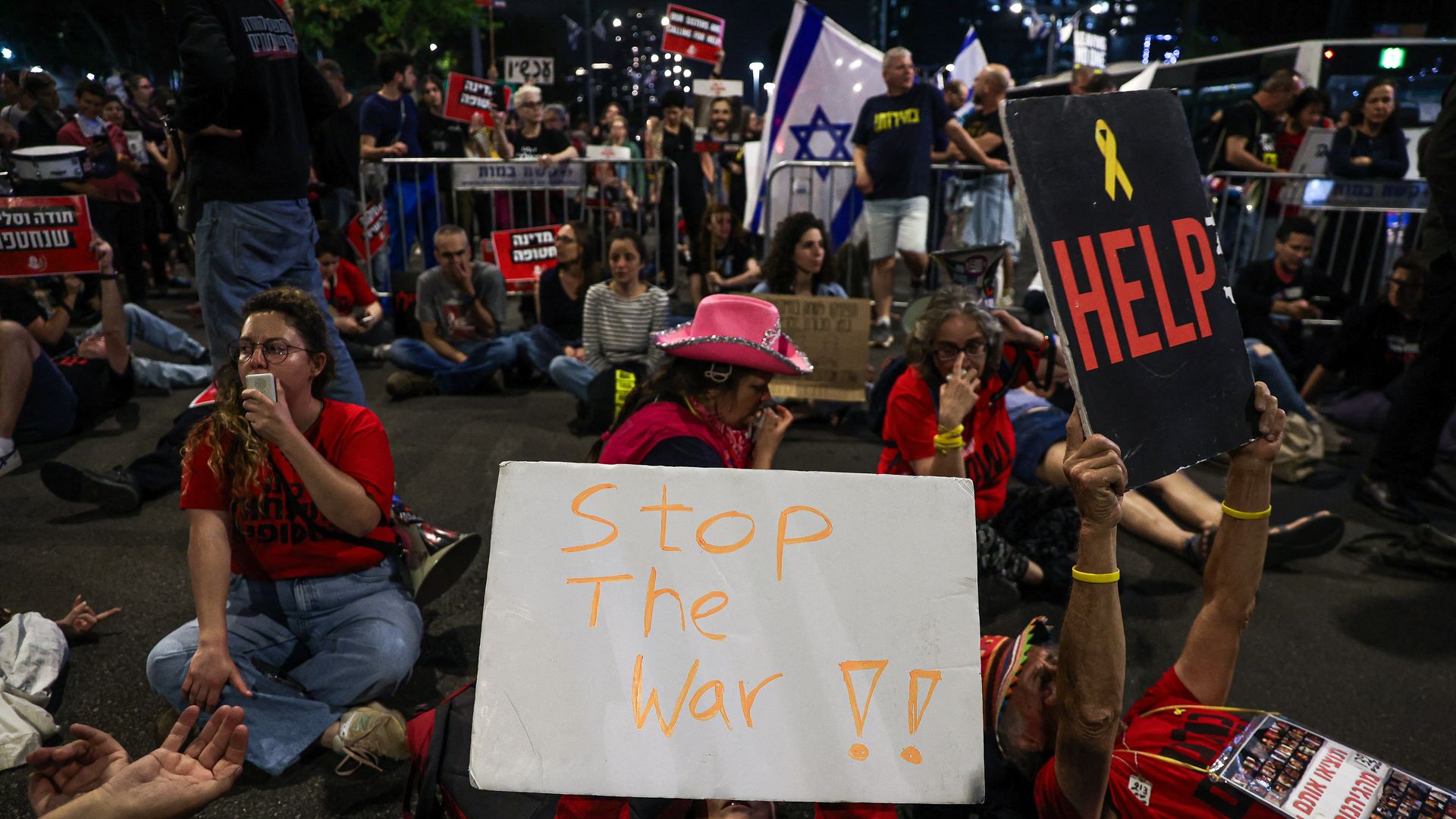 A protesters lies on the ground while holding a sign saying "Stop the war" during a large rally in Tel Aviv held by the relatives and supporters of hostages against the Prime Minister Benjamin Netanyahu's government on Monday, May 6, 2024. 