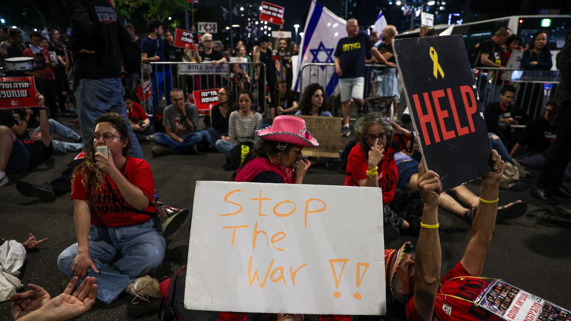 A protesters lies on the ground while holding a sign saying "Stop the war" during a large rally in Tel Aviv held by the relatives and supporters of hostages against the Prime Minister Benjamin Netanyahu's government on Monday, May 6, 2024.