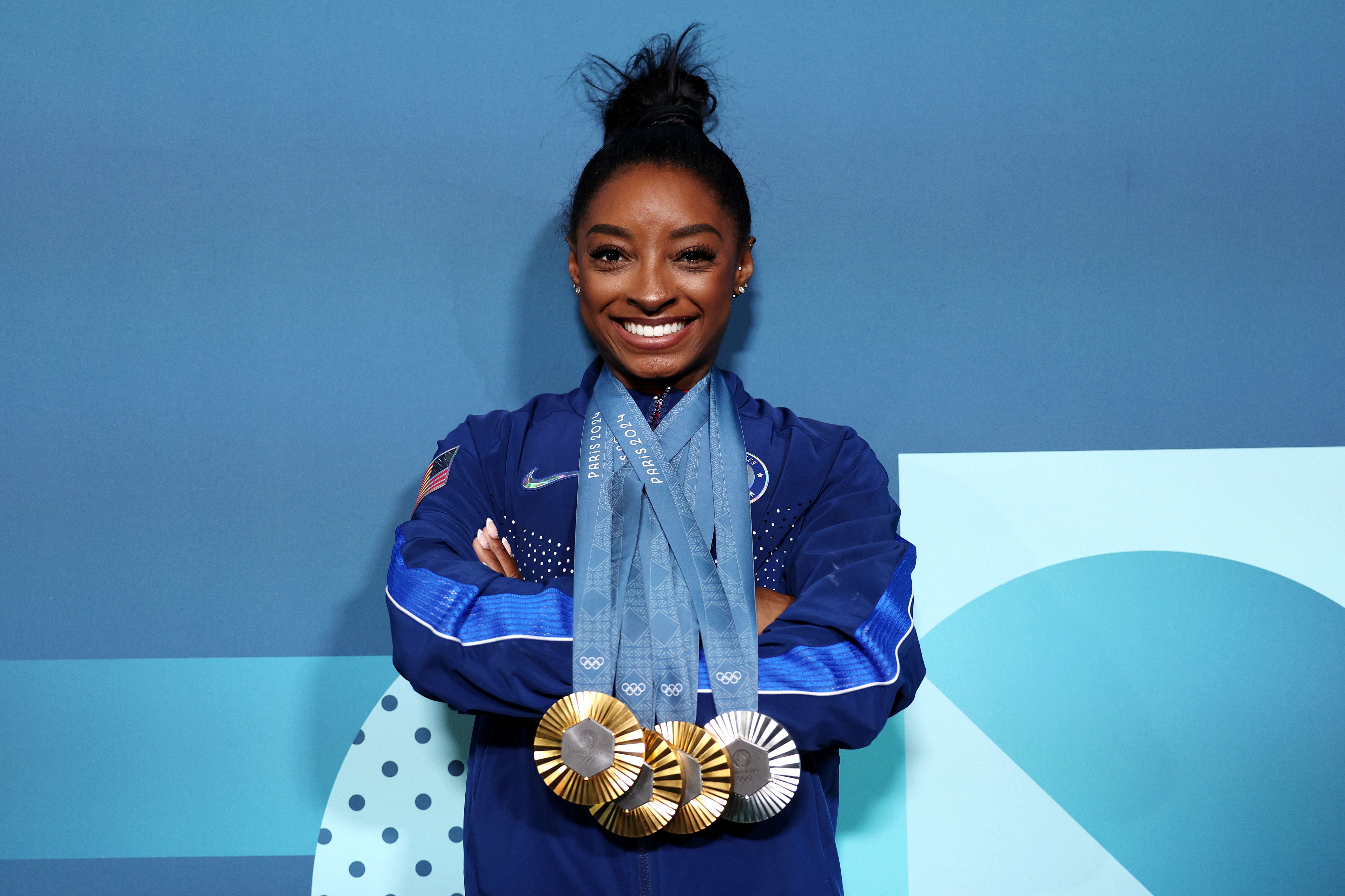 Simone Biles wears three gold and one silver medal at the Olympics.