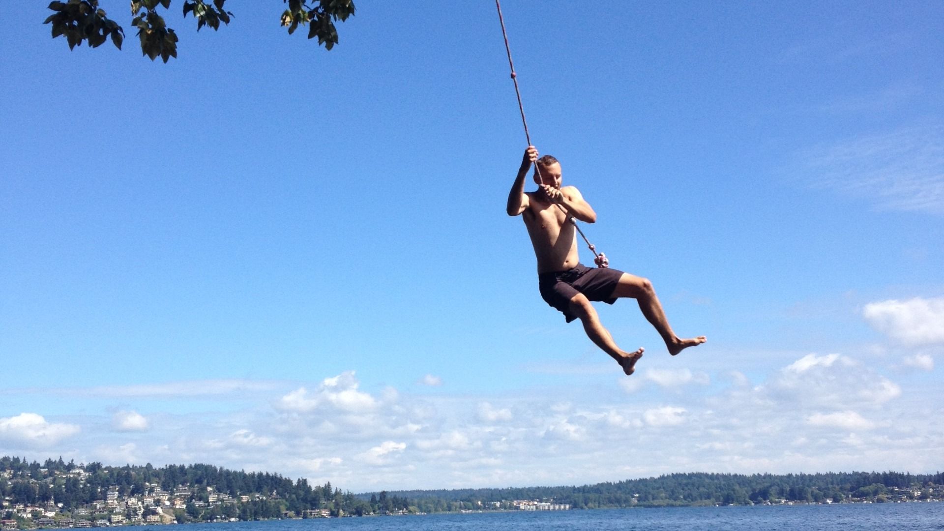 A man swings on a rope swing over Lake Washington.