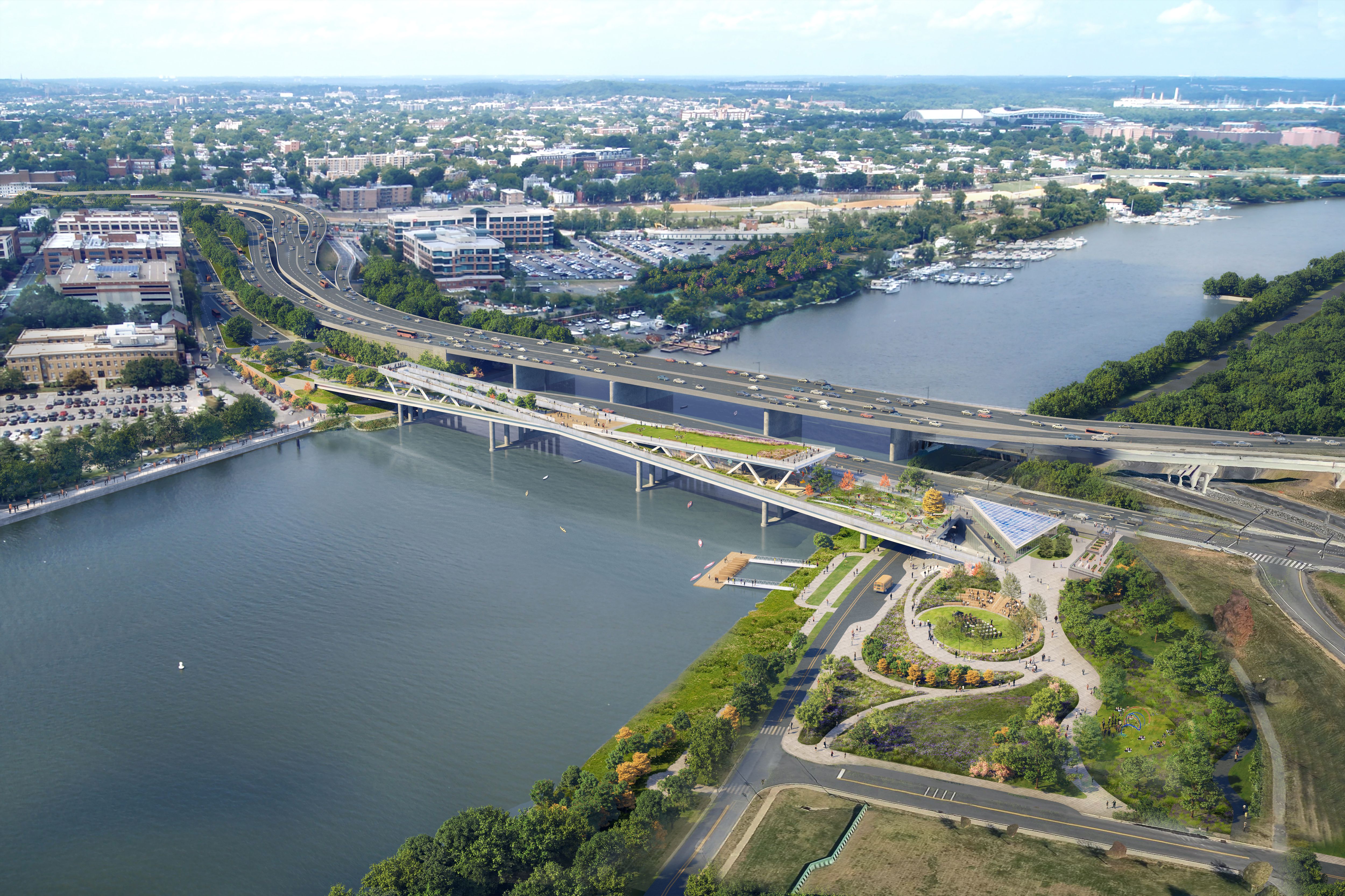 Aerial view of a large river with two bridges crossing it: a busy highway bridge and a pedestrian bridge with green parks and pathways on either side, surrounded by urban buildings and trees.