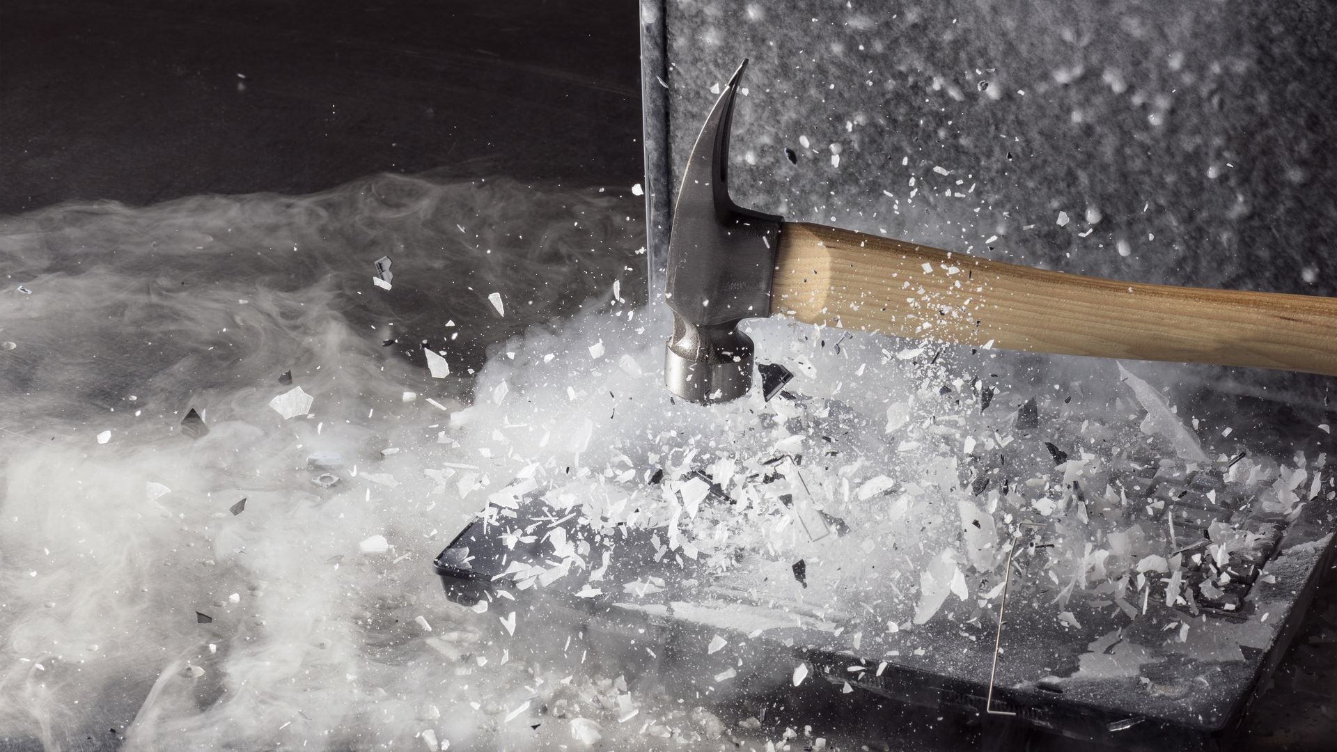 Photo of a hammer breaking ice on a frozen laptop.