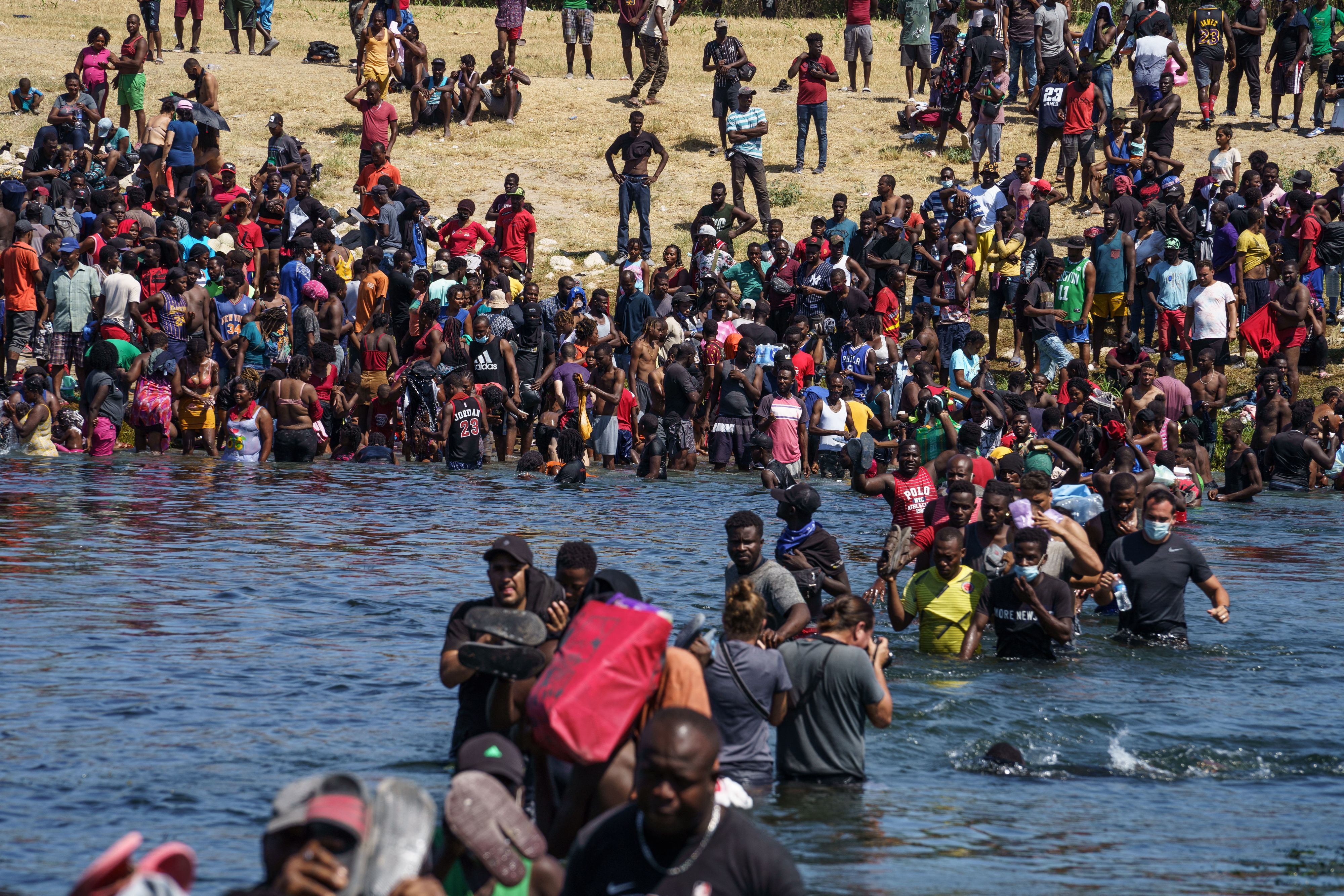 Haitian migrants, part of a group of over 10,000 people staying in an encampment on the US side of the border, cross the Rio Grande river to get food and water in Mexico, after another crossing point was closed near the Acuna Del Rio International Bridge in Del Rio, Texas on September 19, 2021. 