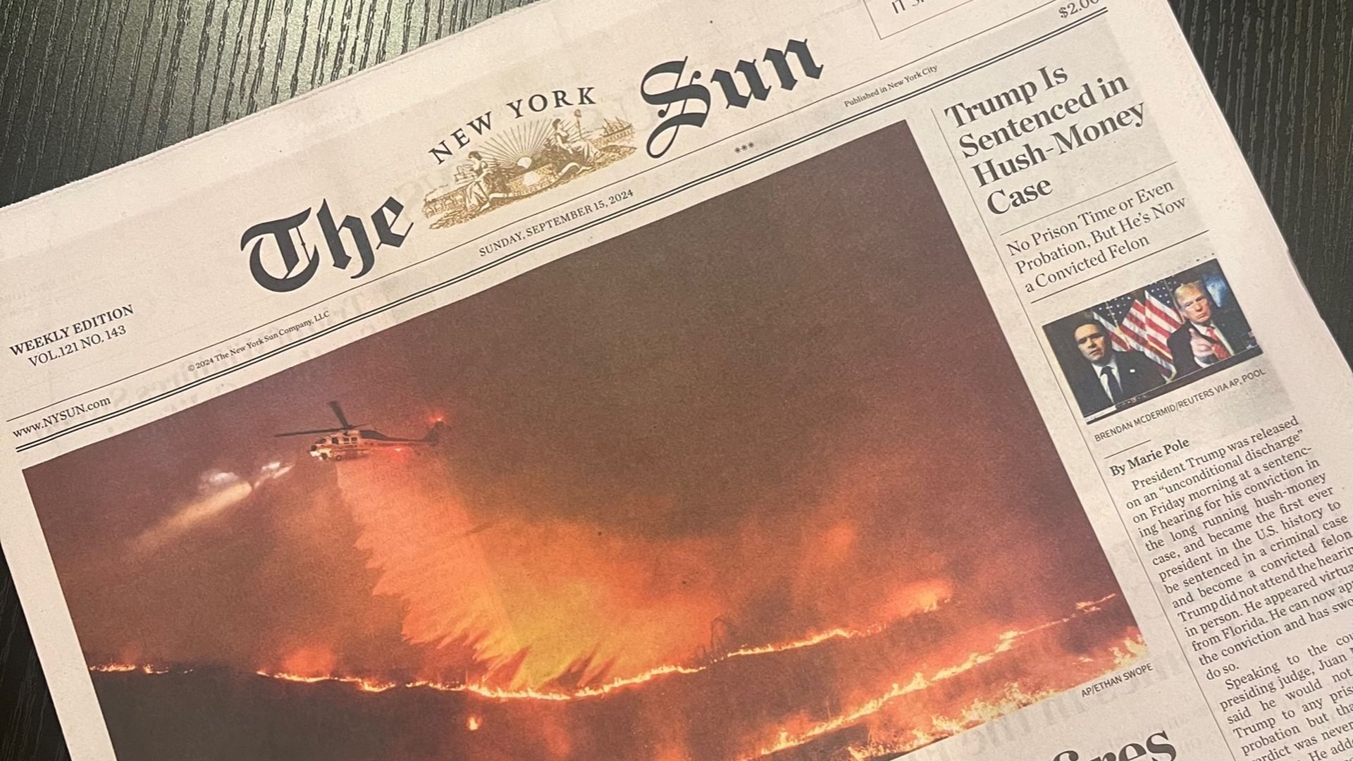 Mock Front page of The New York Sun newspaper dated September 15, 2024, showing a large photo of a wildfire with a firefighting helicopter dropping water. Headlines about wildfires in Southern California and Trump sentenced in hush-money case.
