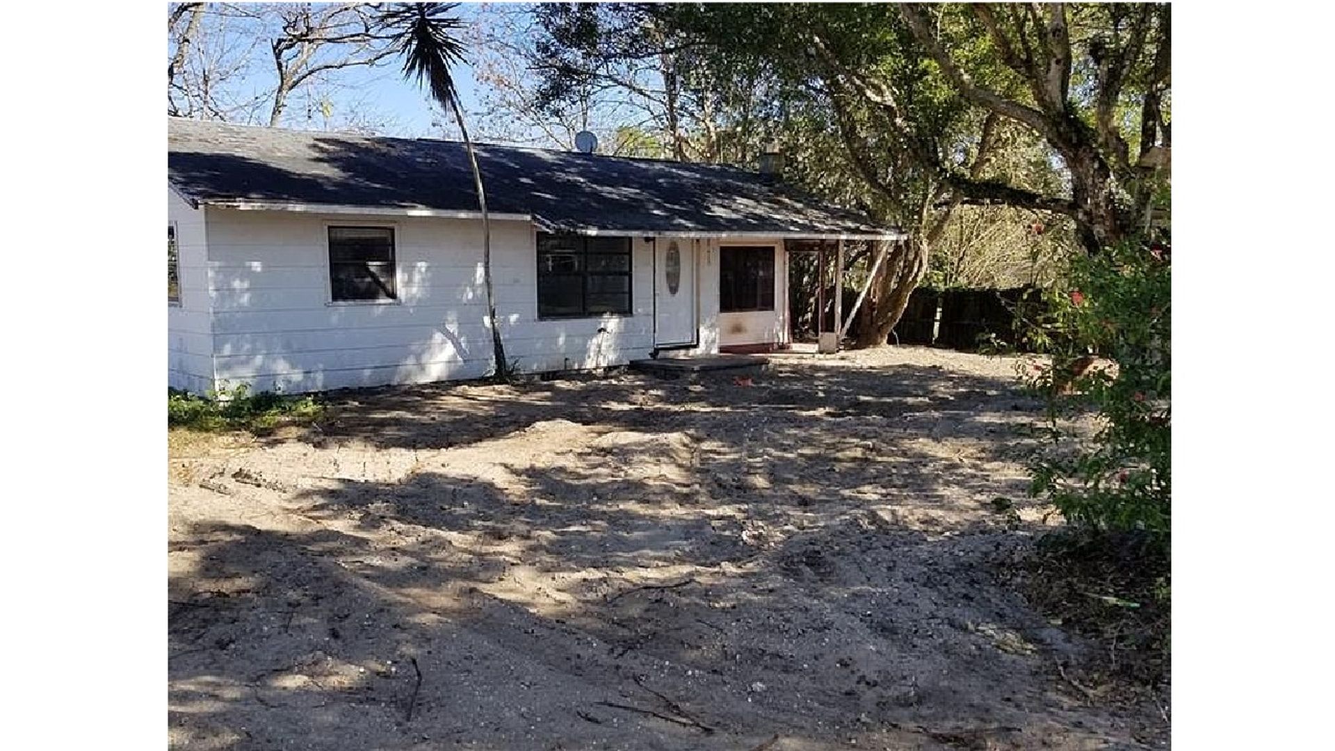 A photograph of a white single-family home in a state of great disrepair.