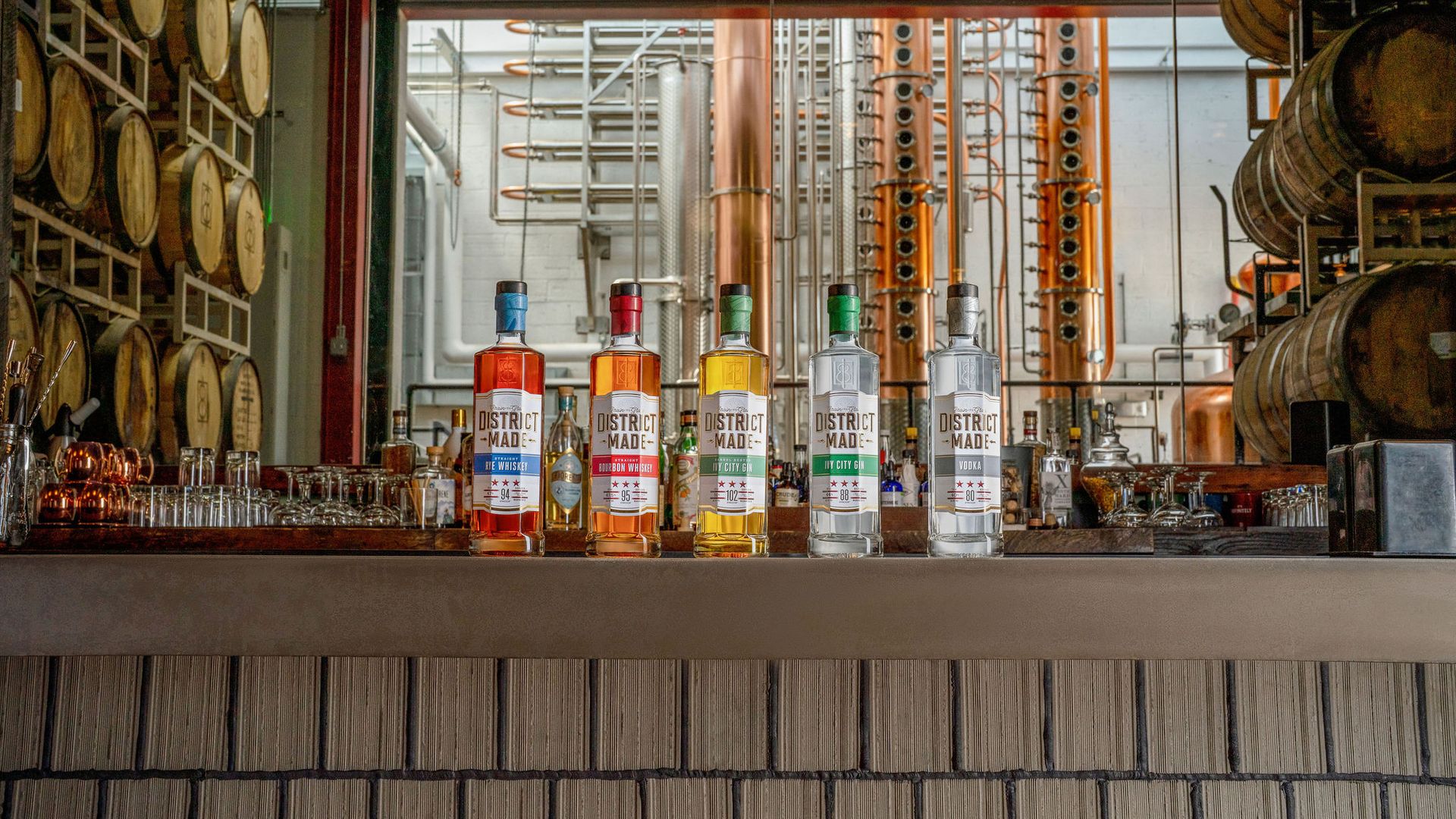 Five liquor bottles of District Made spirits sit on a bar