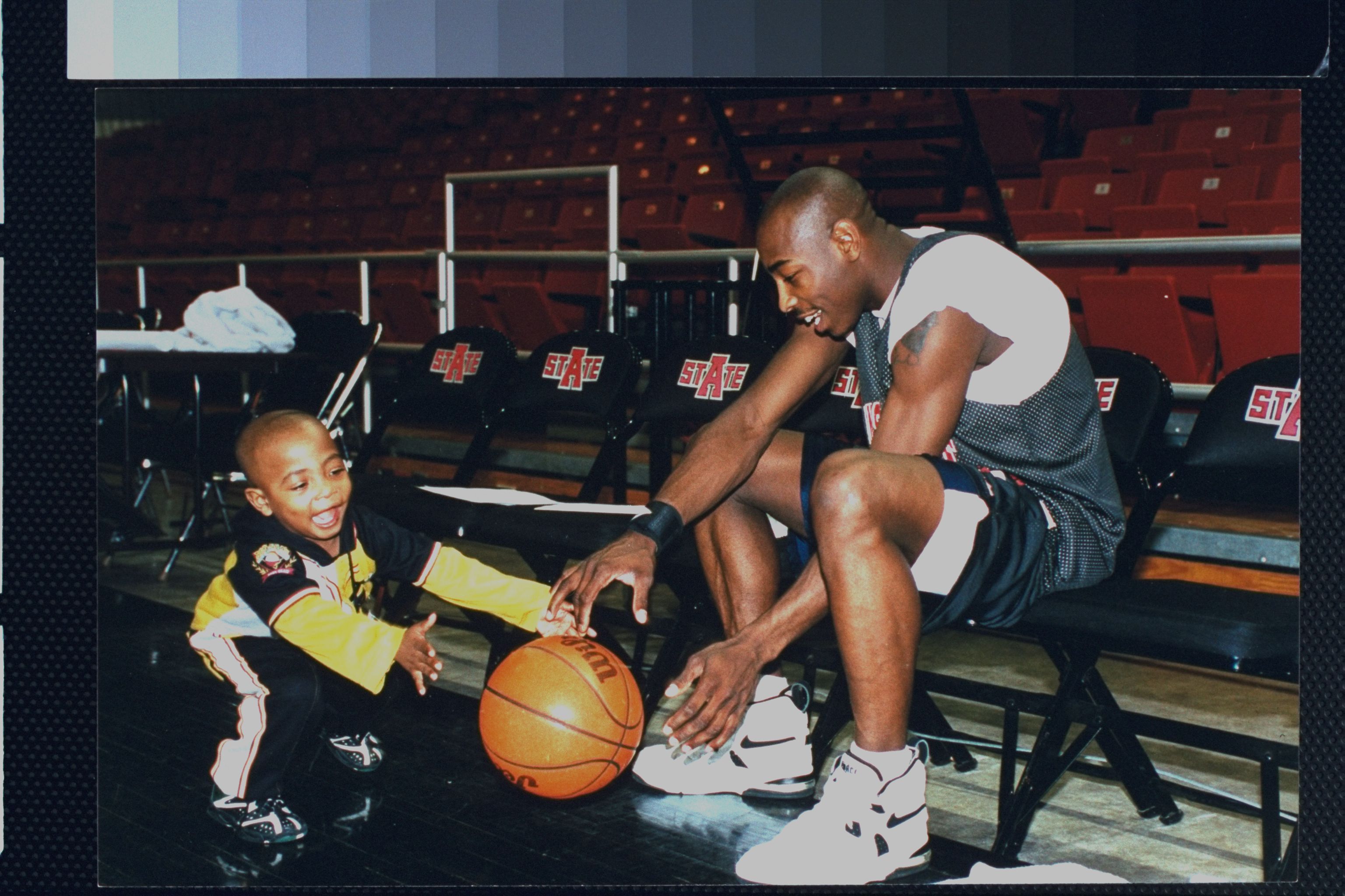 Photo of a man dribbling a basketball with a baby 
