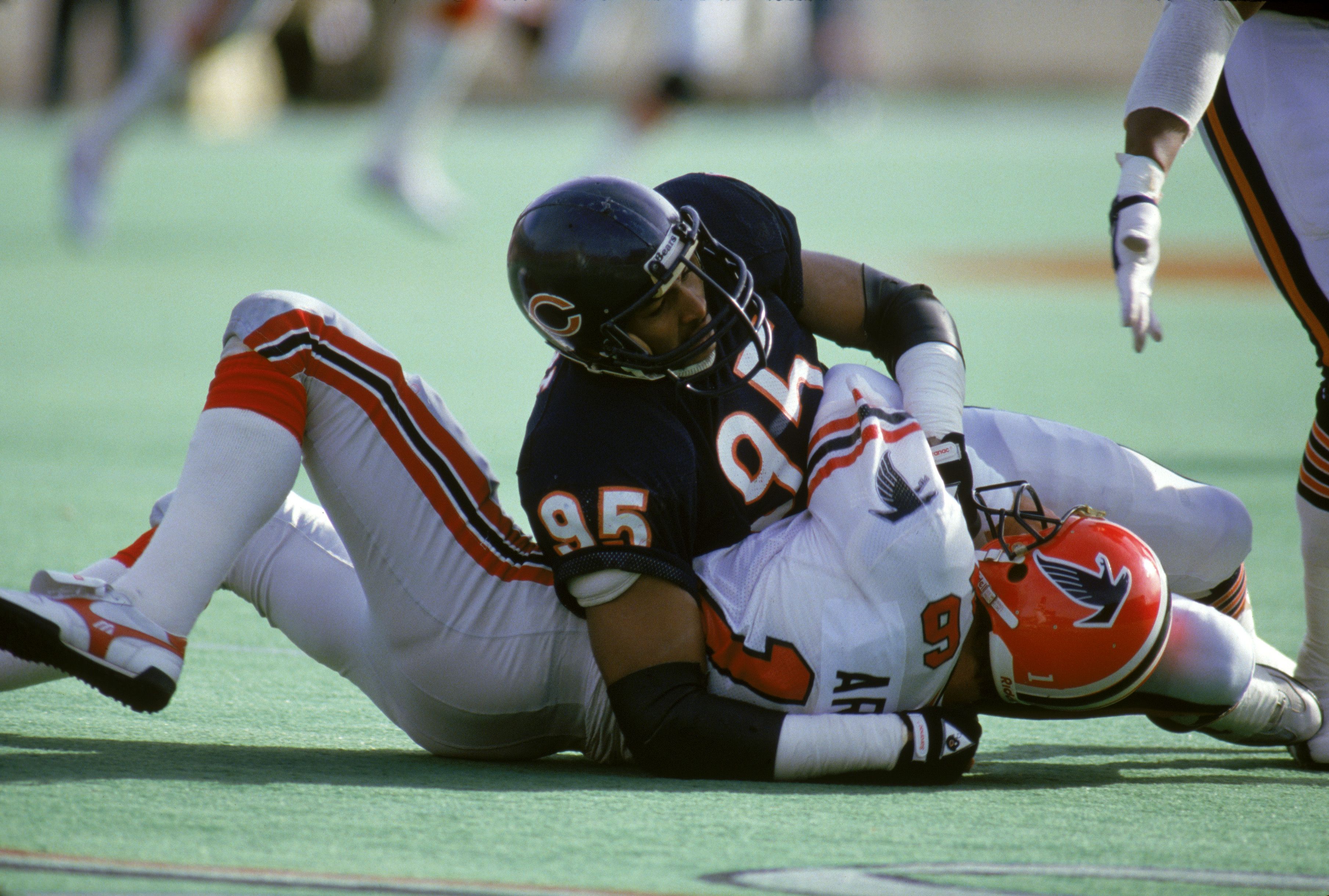 Chicago Bears Richard Dent on top of Atlanta Falcons David Archer, tackling him during a game.