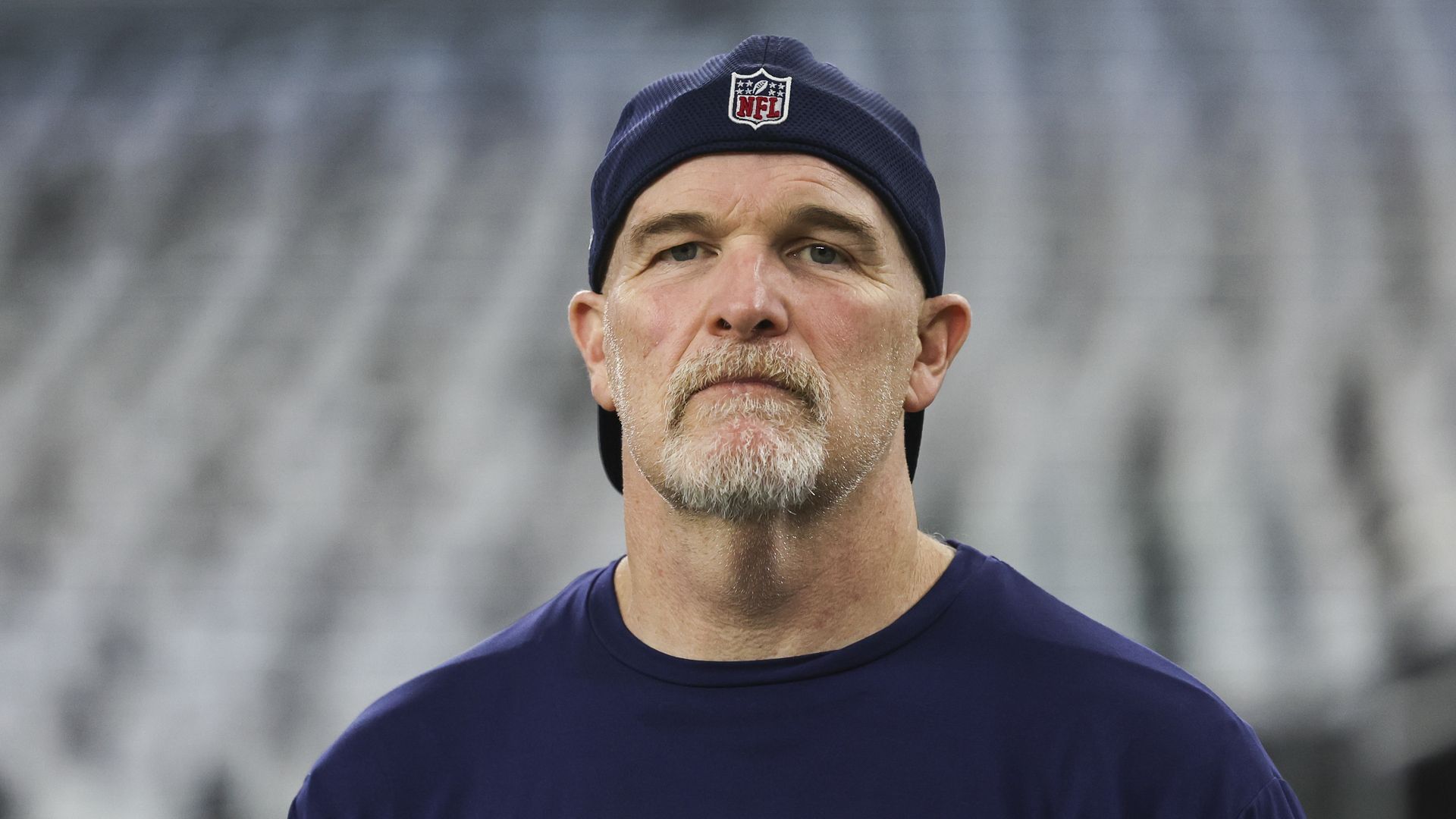 Dan Quinn looks at the camera while wearing a backwards NFL cap.