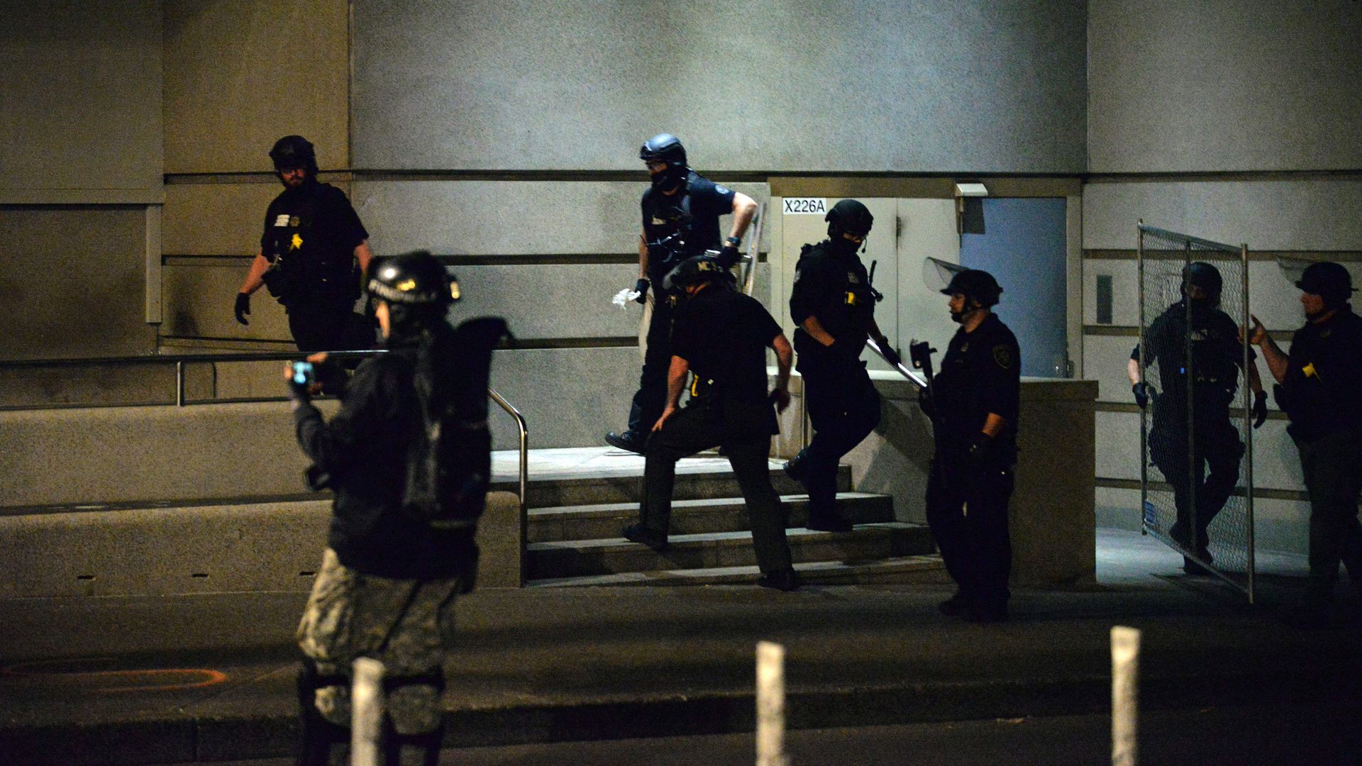 Police officers remove fencing that block the doors of the Multnomah County Justice Center
