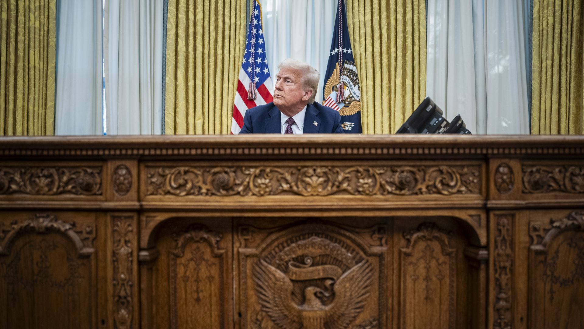 A photo of President Donald Trump sitting behind his desk in the Oval Office.