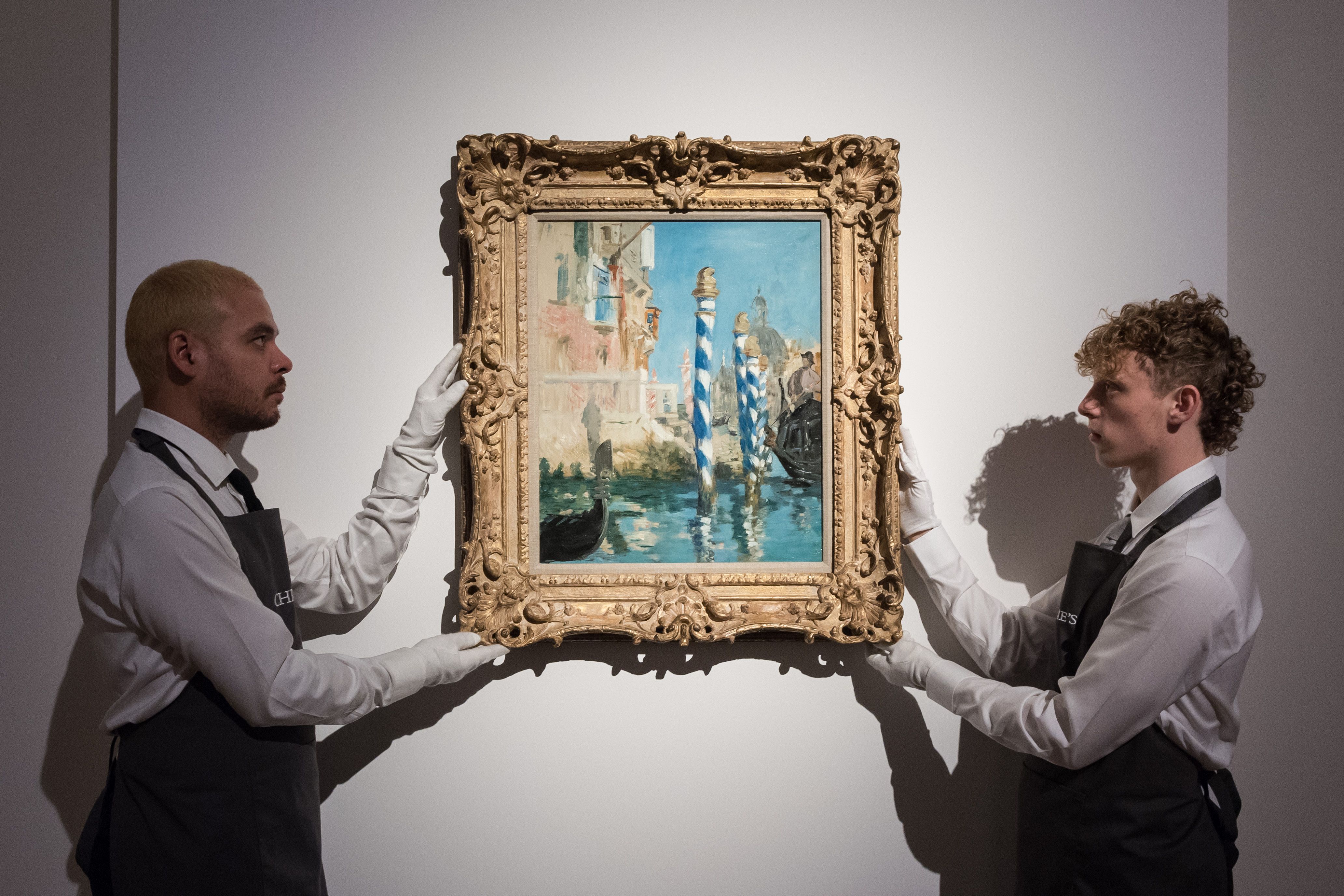 Art handlers hold a painting titled 'Le Grand Canal a Venise' by Edouard Manet on display in London.