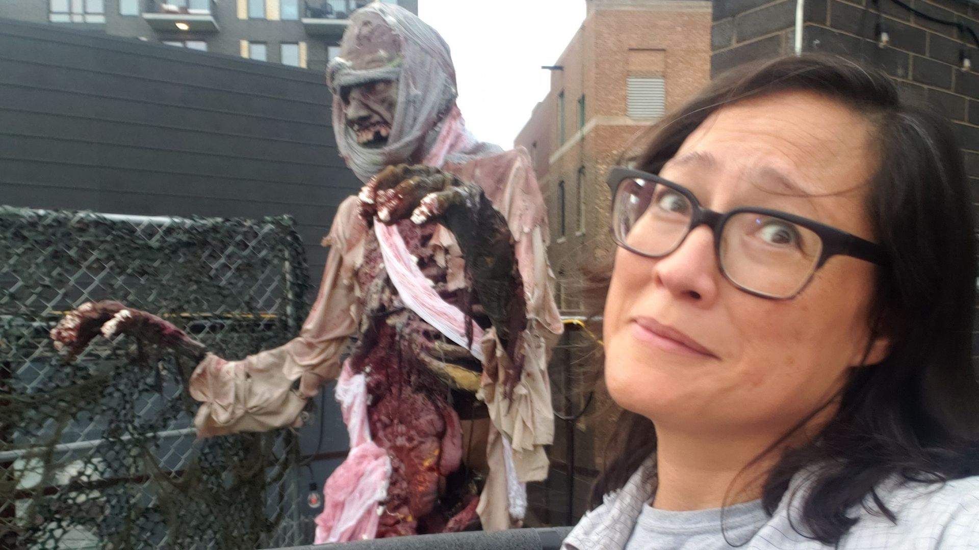 A zombie figure with a woman in glasses next to it.