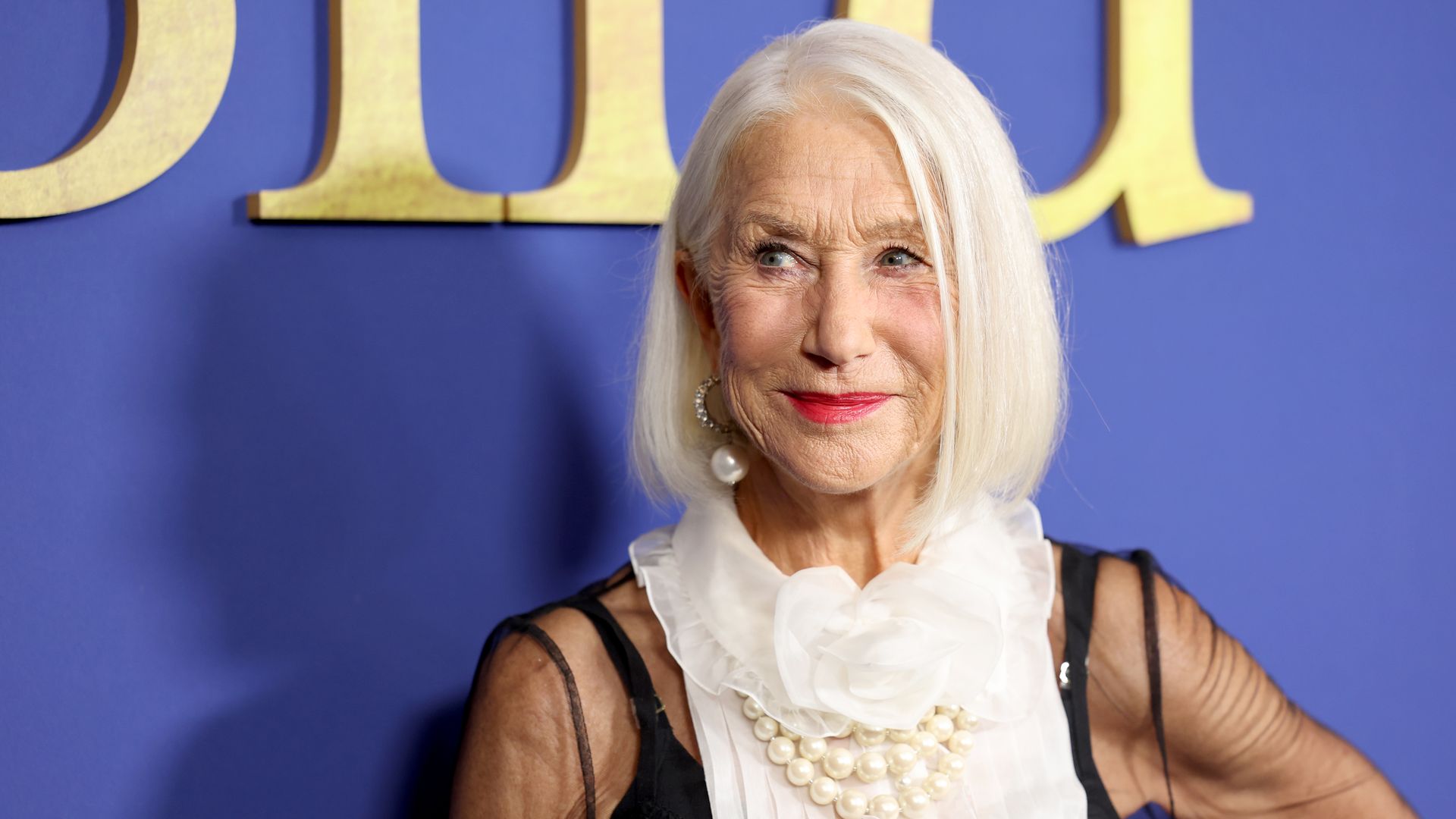 A close-up photo of Helen Mirren as she smiles on a red carpet.