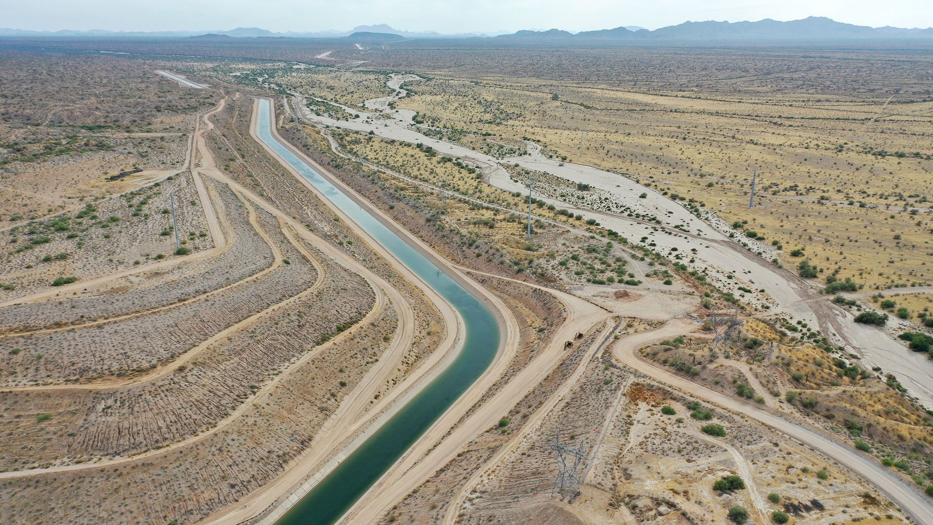 A canal filed with water snakes through the desert.