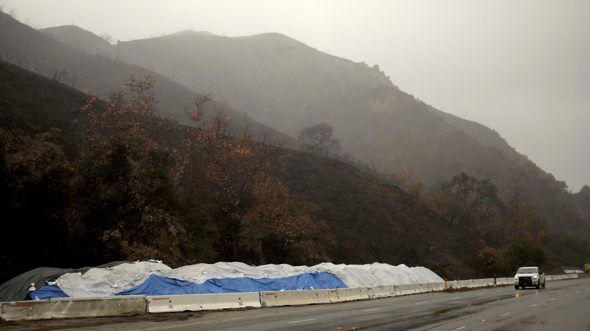 A truck drives along Palisades Drive where K-rail has been set up to prevent possible mudslides and debris flow from the Palisades fire in Pacific Palisades on February 12, 2025. 