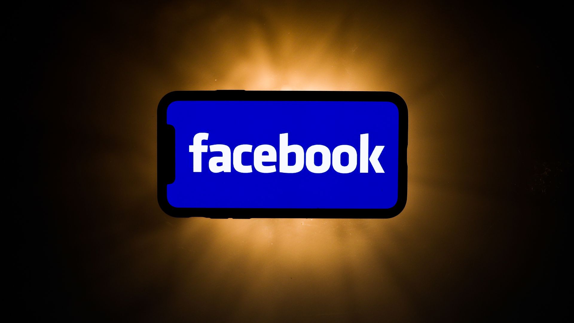 A photo illustration of a smartphone with the Facebook logo displayed prominently on it.