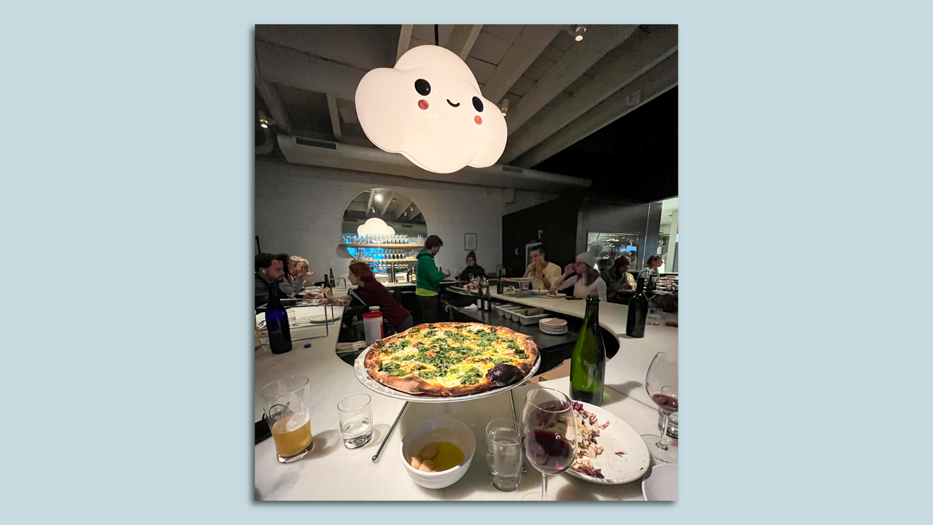 A platter of pizza and a class of red wine served at the counter of Pizzeria Beddia in Philadelphia.