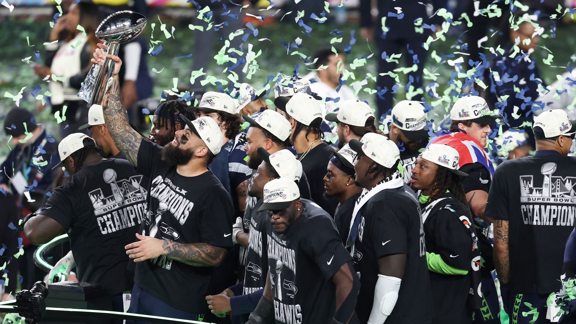 Seahawks celebrate with confetti falling while one holds up the Lombardi trophy. 