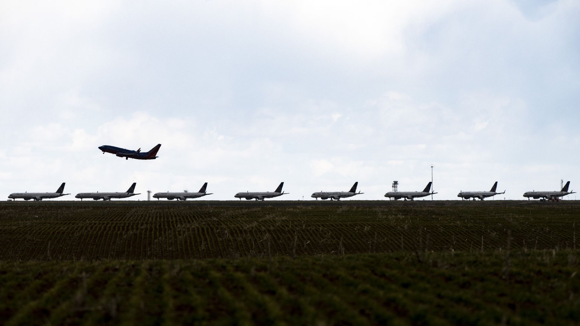 A Southwest Airlines flight takes off as United Airlines planes sit parked on a runway