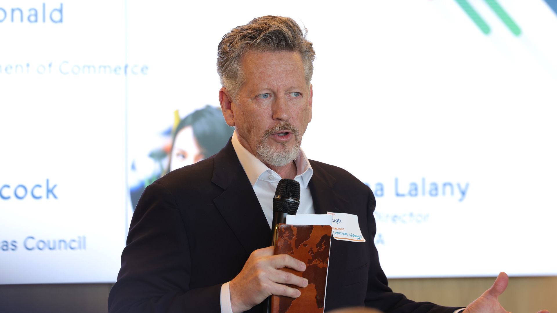 A photo of Arkansas Sec. of Commerce holding a microphone and speaking to a group of people. 