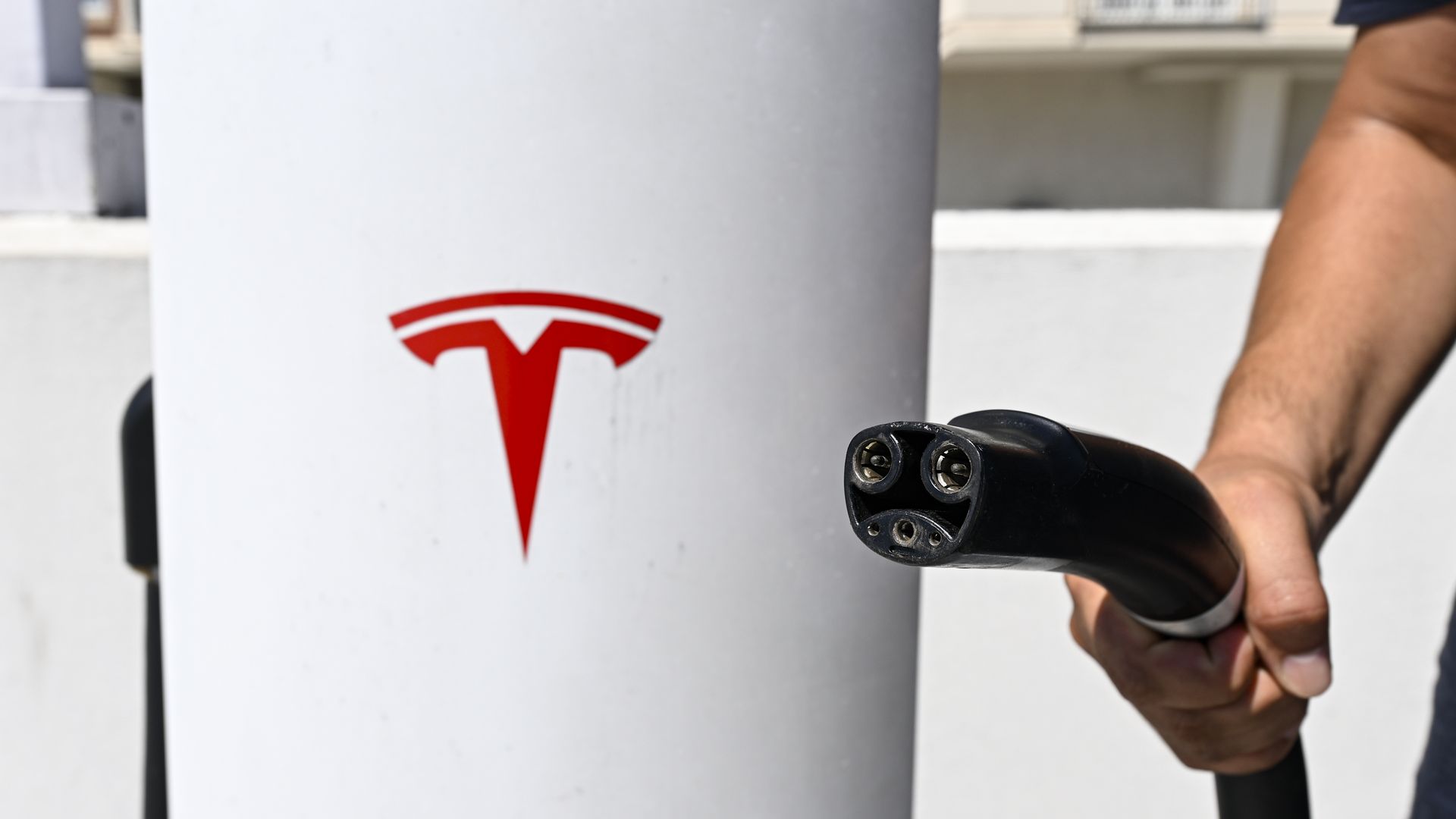 A person holds an electric car charging plug