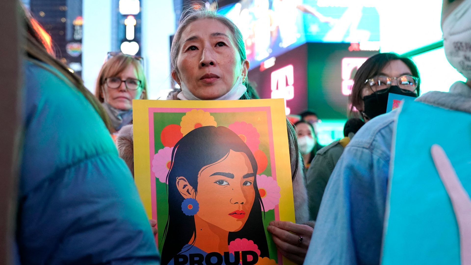 Photo of a person holding a sign showing an Asian woman, with the words "Proud to be Asian"