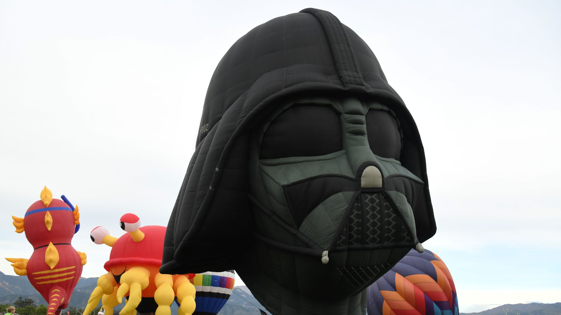 Darth Vader ballon several other colorful hot air balloons in various stages of inflation take shape in a grassy field in Memorial Park. 