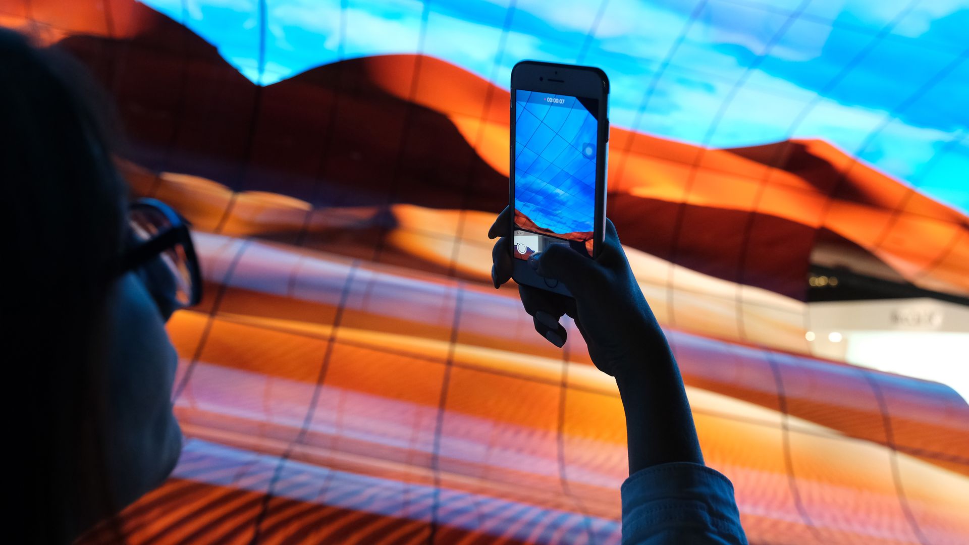 A visitor photographs a display of curved OLED televisions at the LG stand at the 2019 IFA home electronics trade fair in Berlin